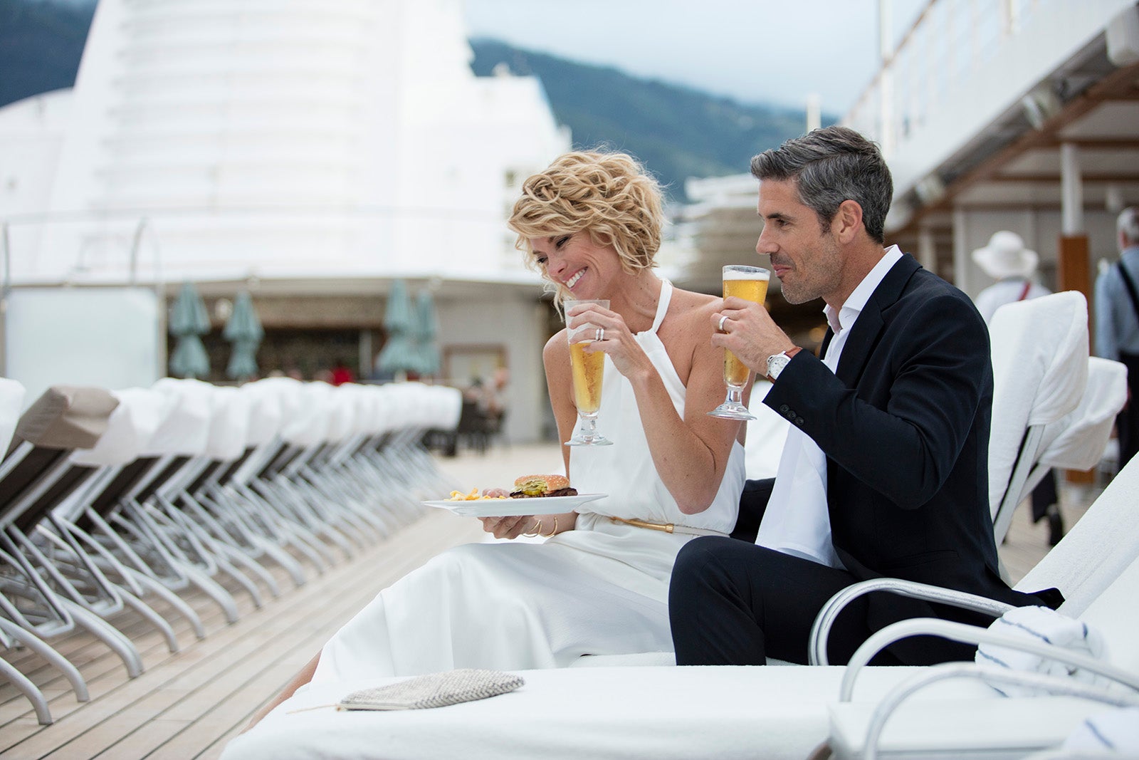 Couple in formalwear drinking Champagne on cruise ship deck
