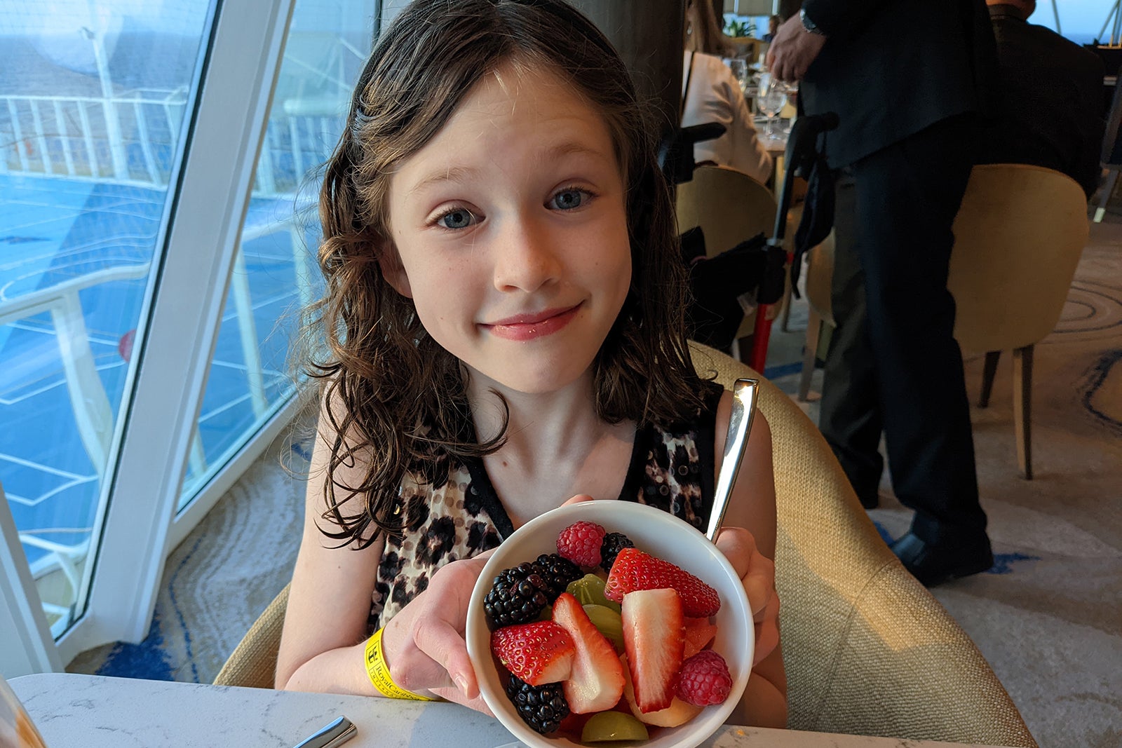 Young girl in restaurant holding bowl of fruit