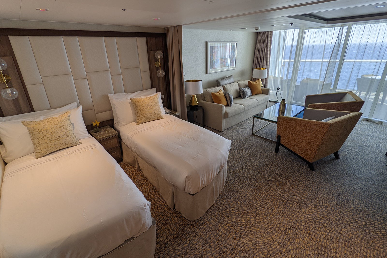 Suite with twin beds and seating area on cruise ship