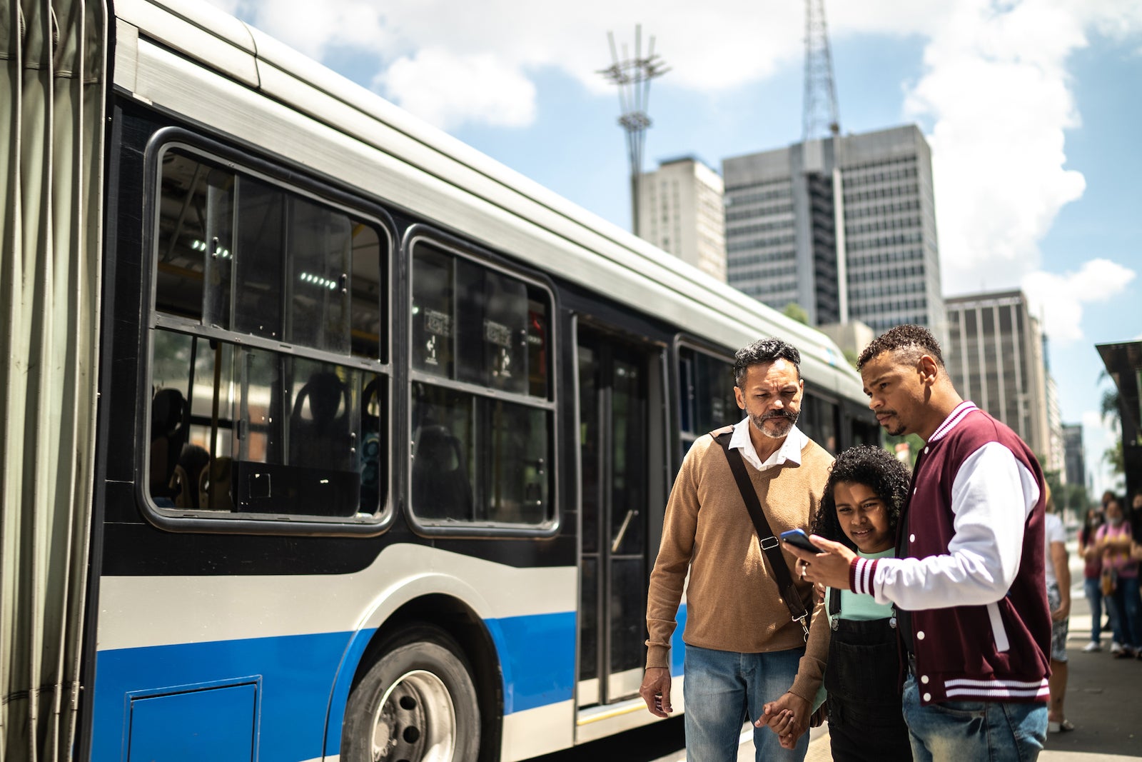 Gay couple with daughter using the mobile phone in the street