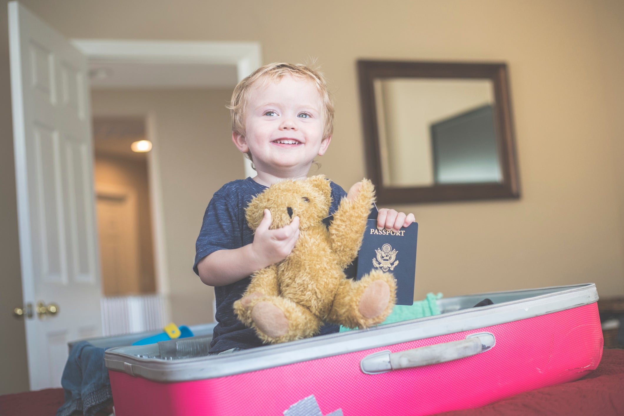 Child sits on suitcase being packed for a trip