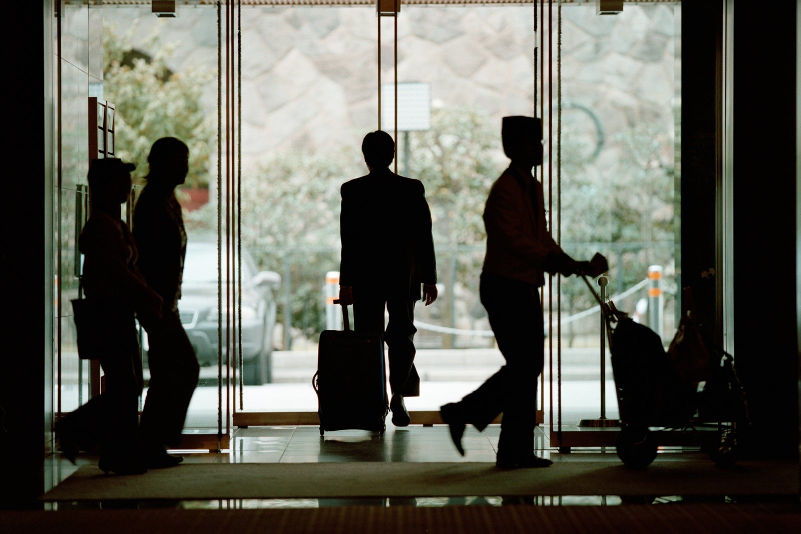 People carrying luggage in lobby, silhouette