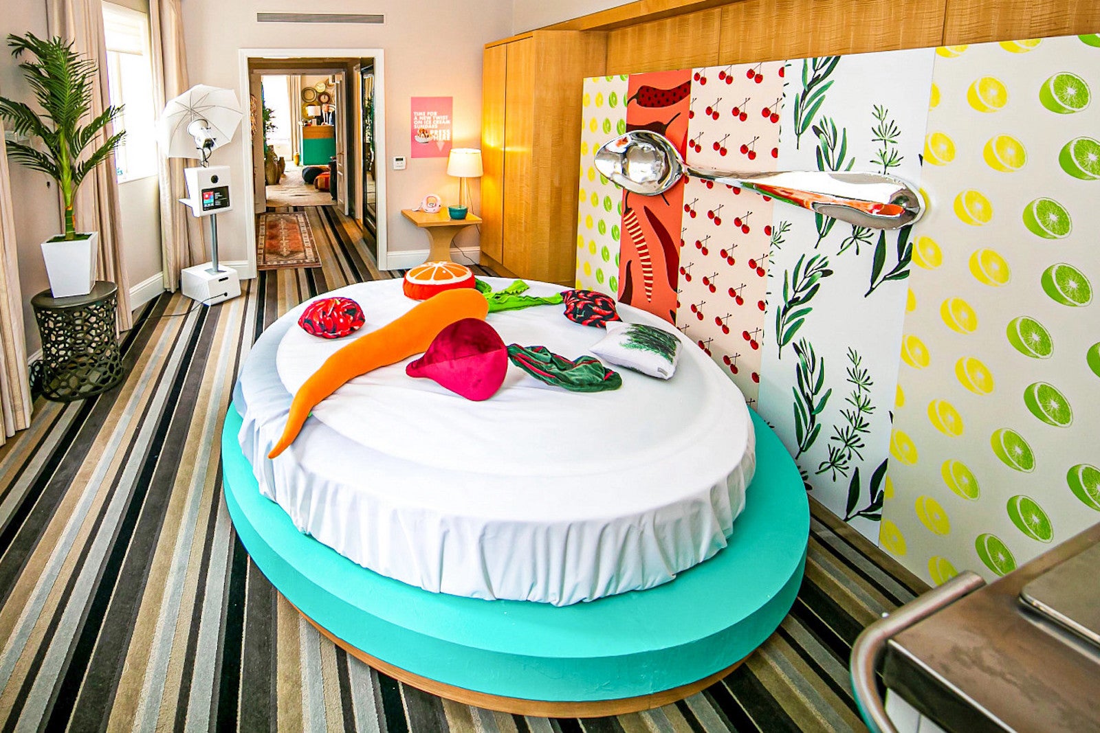 hotel room with food-themed wallpaper, circular bed with food-shaped pillows