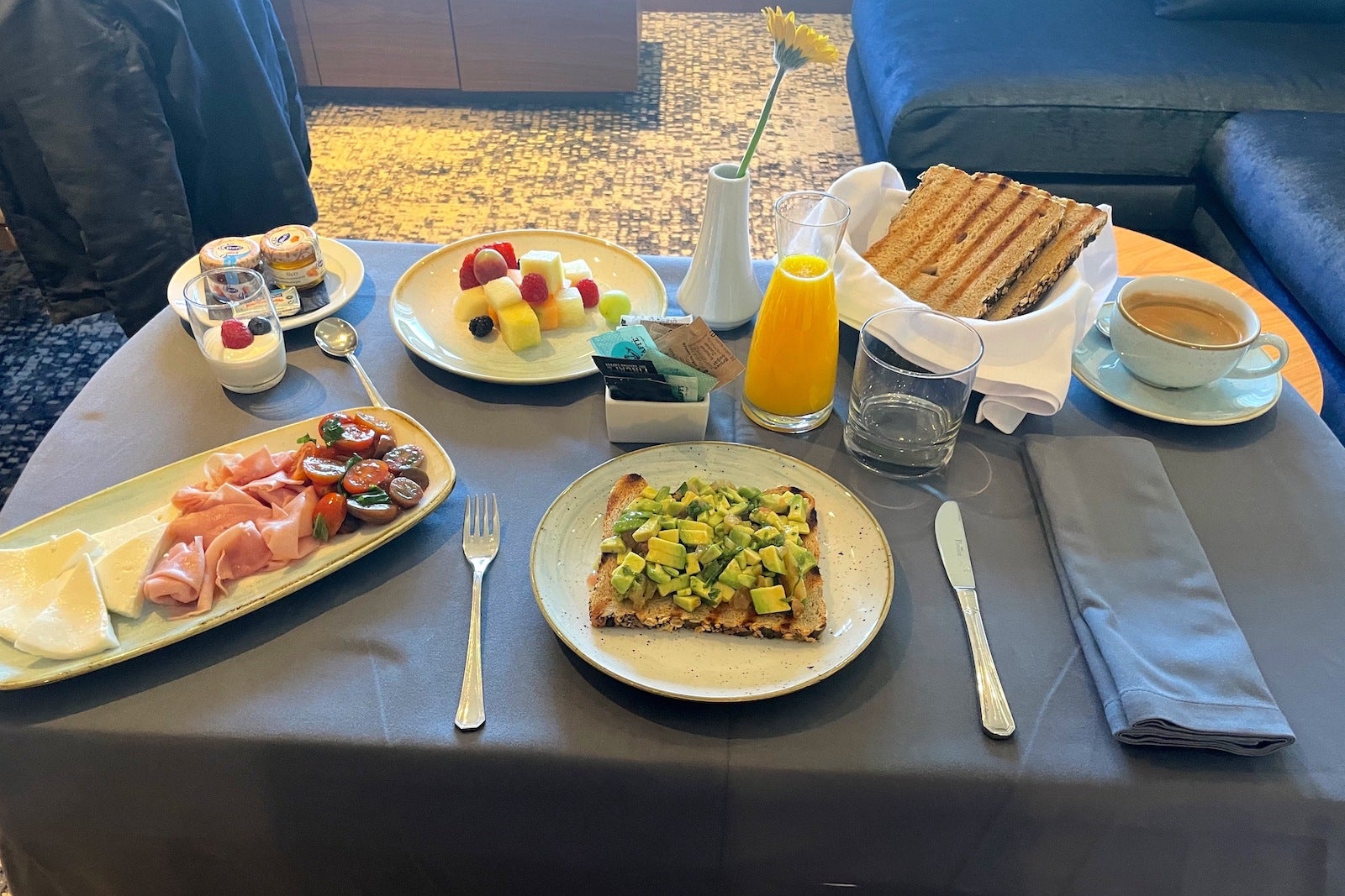 breakfast tray with avocado toast, meat and cheese tray, bread fruit and coffee