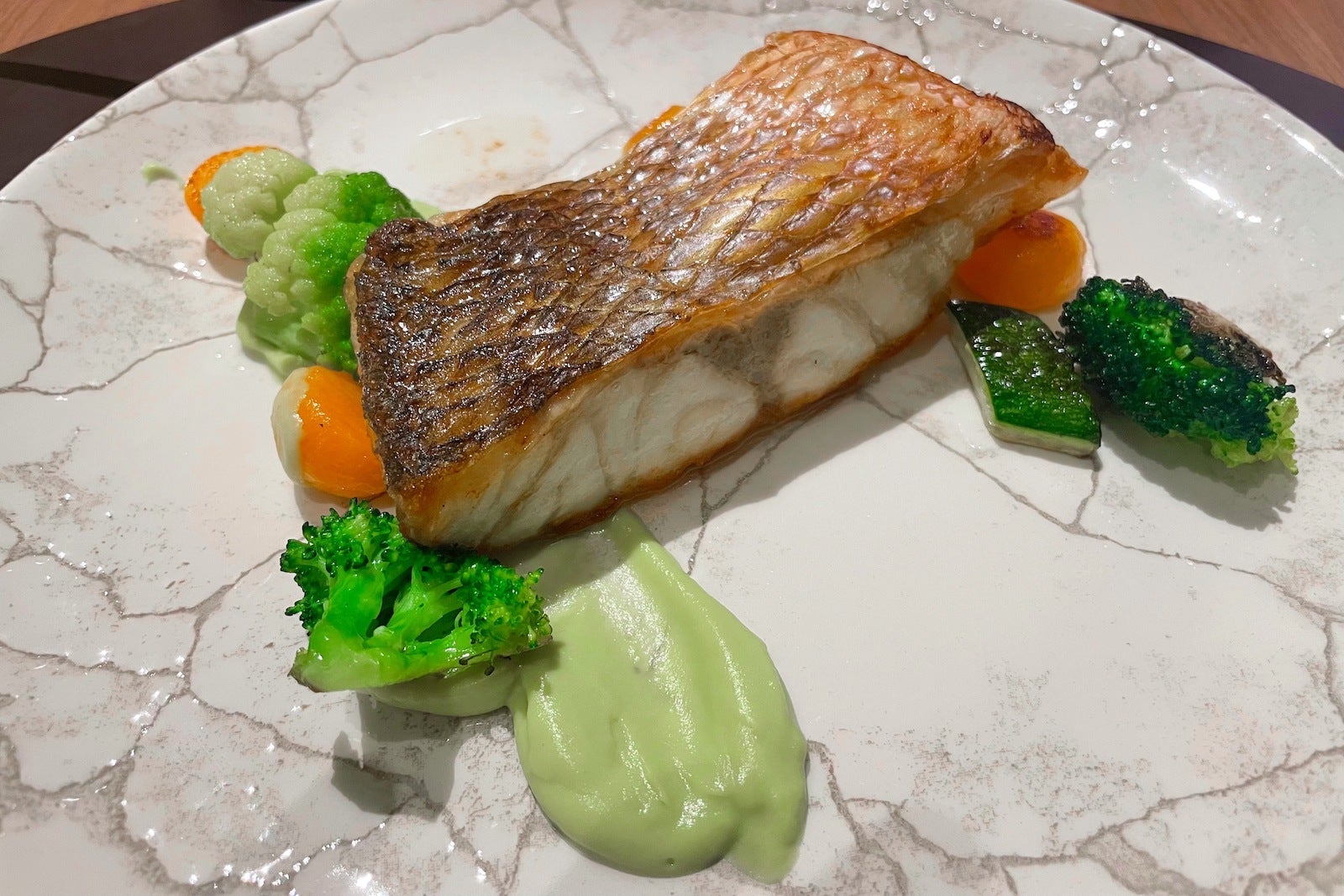 grilled fish on plate with green and orange veggies