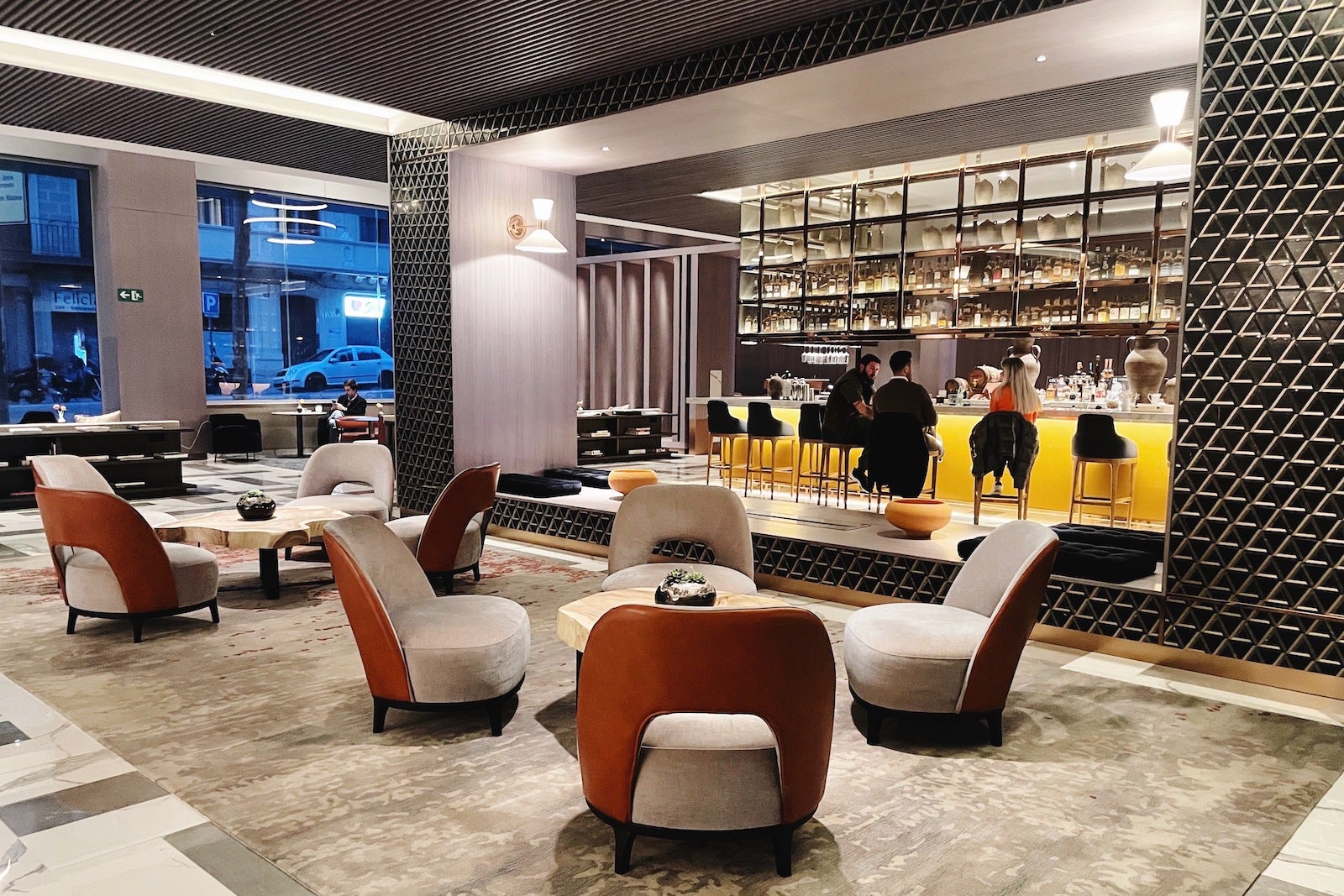 hotel lobby bar with living room-style seating and beautiful gold bar framed by black, geometric wall