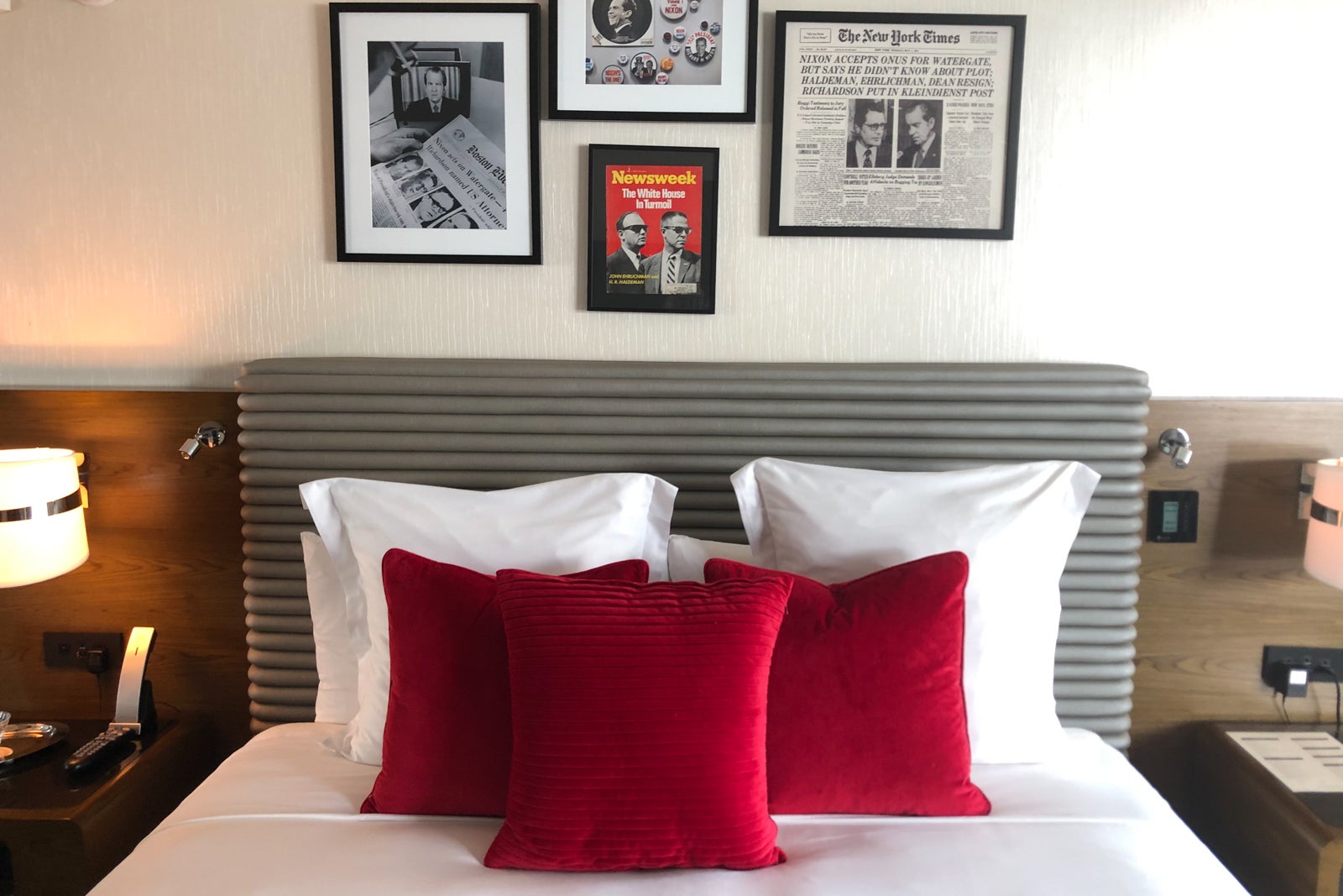 The clean lines of the gray headboard, the deep red velvet pillows on top of crisp white sheets and the Nixon-related art above the bed make the Scandal Room's sleeping area cozy yet period-appropriate.