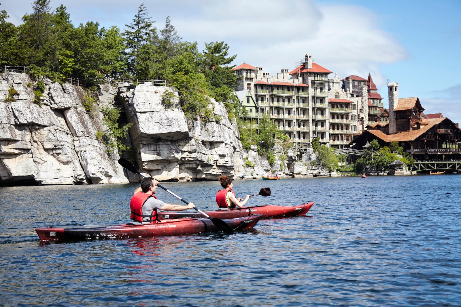 two people kayaking on lake in front of castle resort