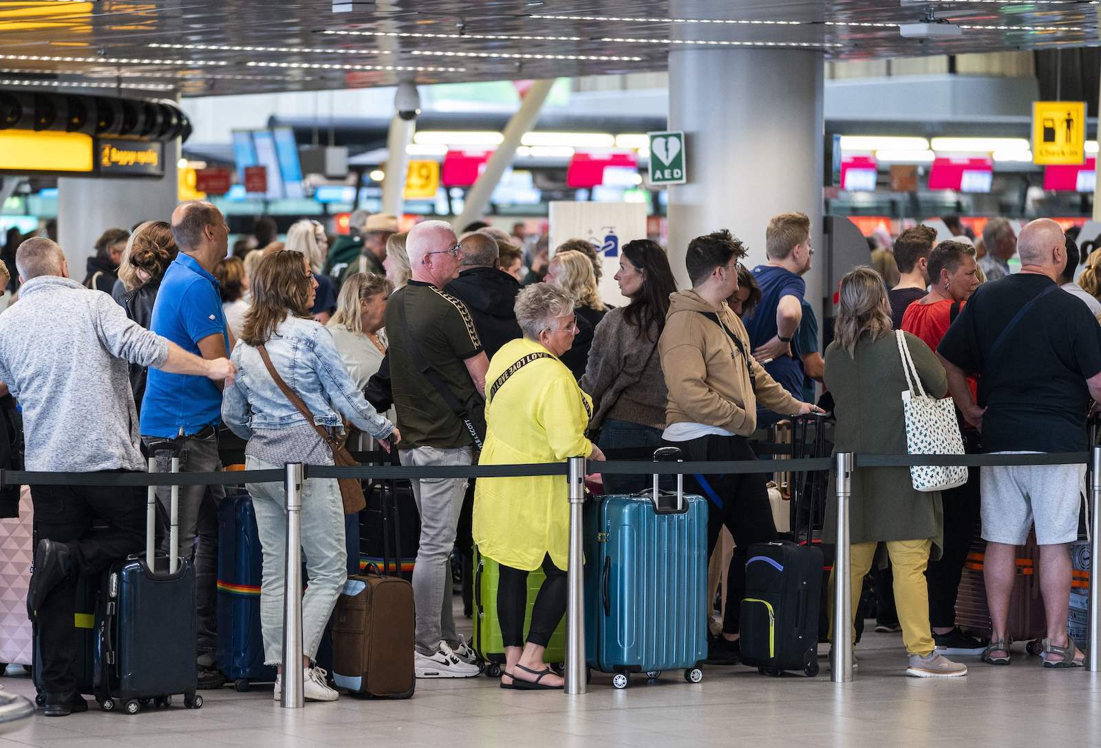crowds wait in a long line at Amsterdam Schiphol Airport
