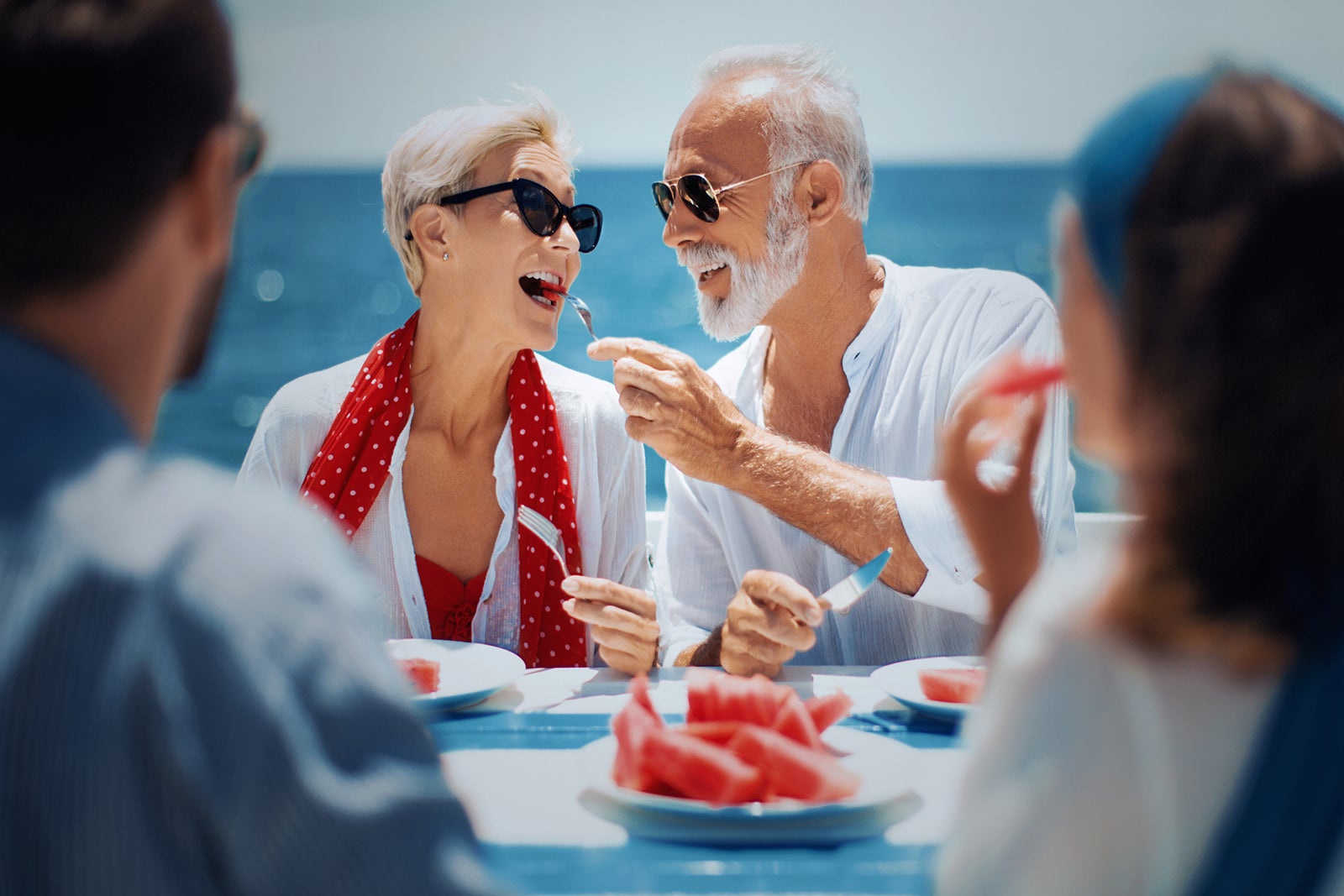 Older couple enjoying meal with the ocean behind them
