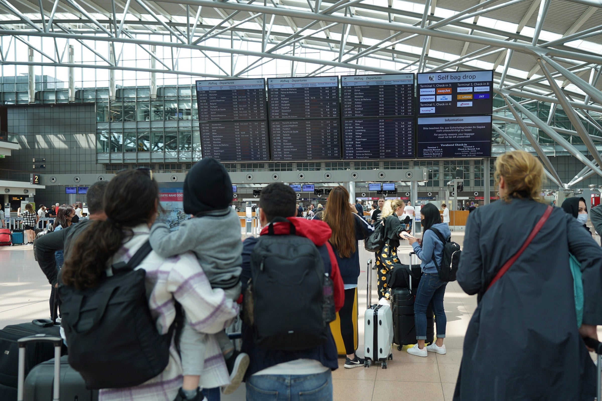 People looking at a flight board in Hamburg airport