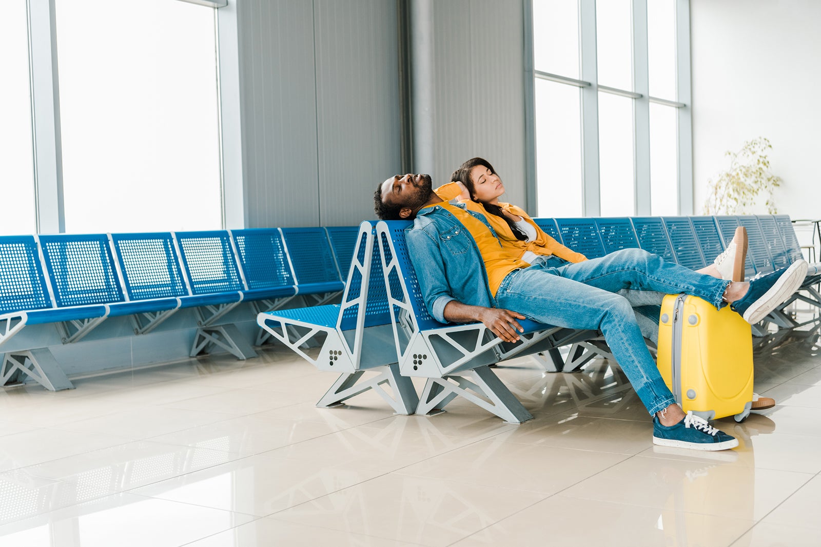 tired african american couple sleeping in departure lounge in airport