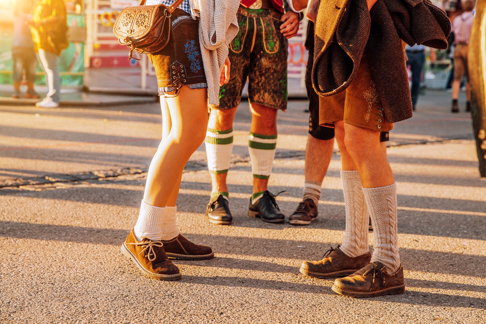 Visitors in lederhosen walking through beer festival fairgrounds