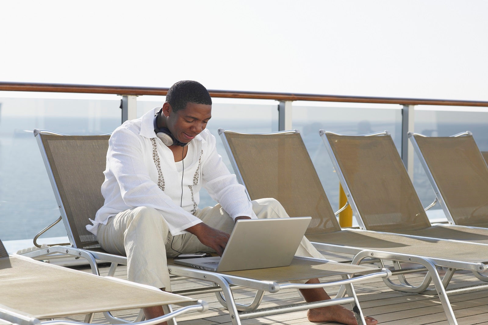 Mature man using laptop on ship deck