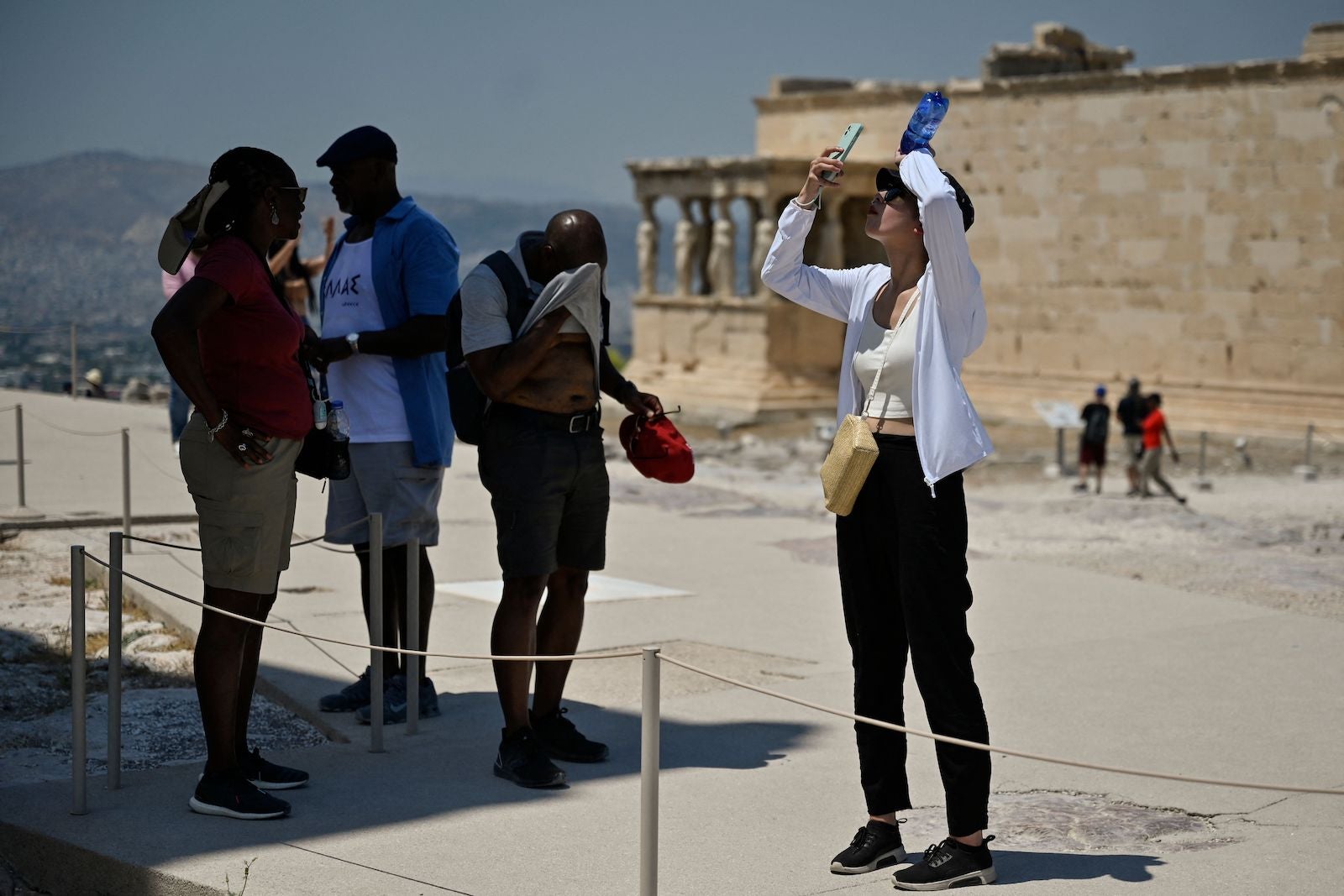 Tourists stand in the shade while visiting the Acropolis
