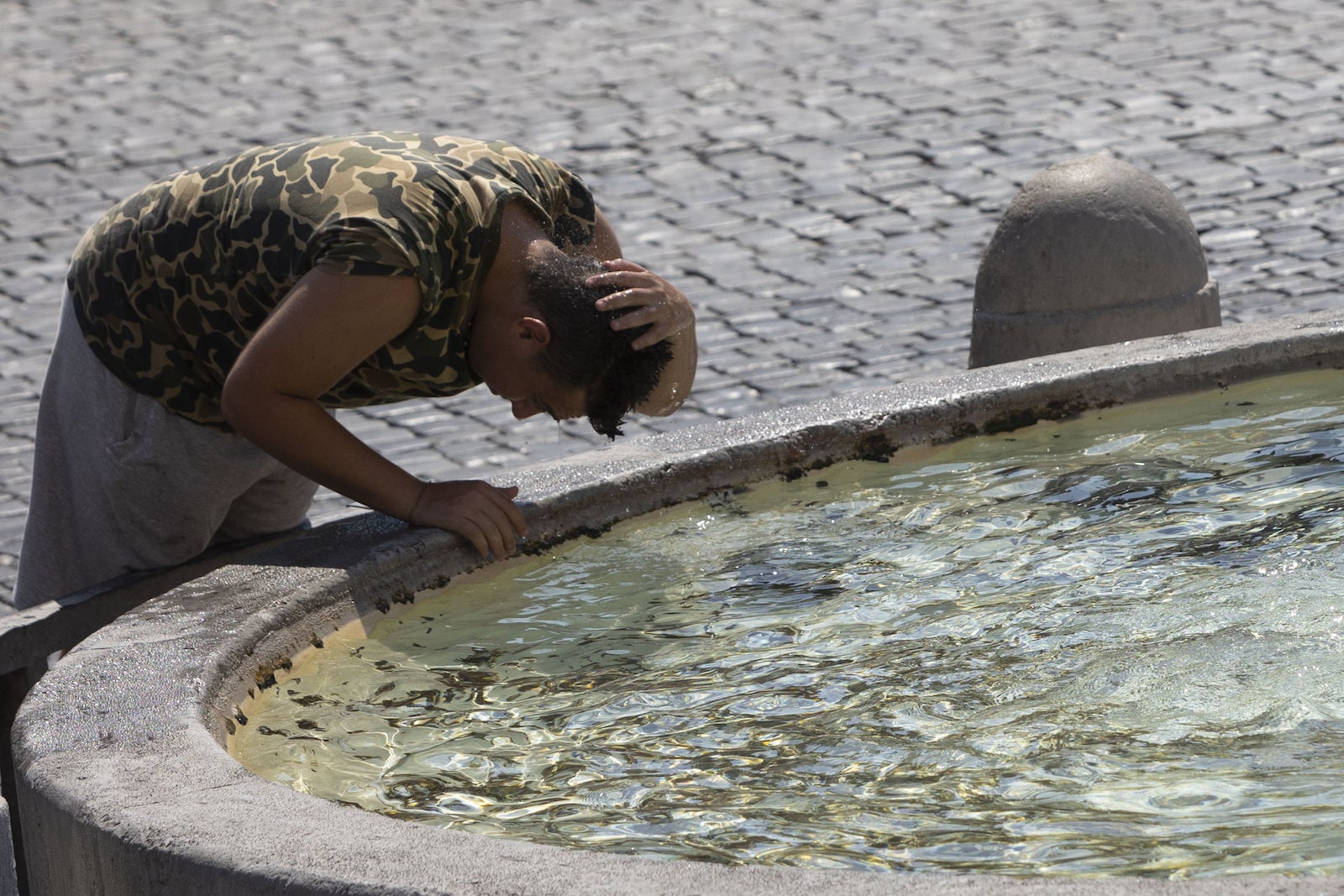 A tourist refreshes himself in the Piazza del Popolo in Rome