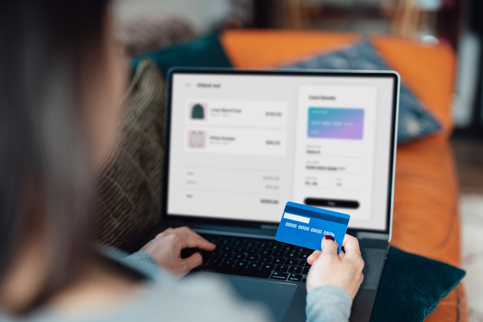 Above the shoulder view of a woman shopping clothes online on laptop, making payment with credit card. Enjoying seasonal sales. Shopaholic concept. Cyber security idea. Close up shot. Laptop screen mockup.