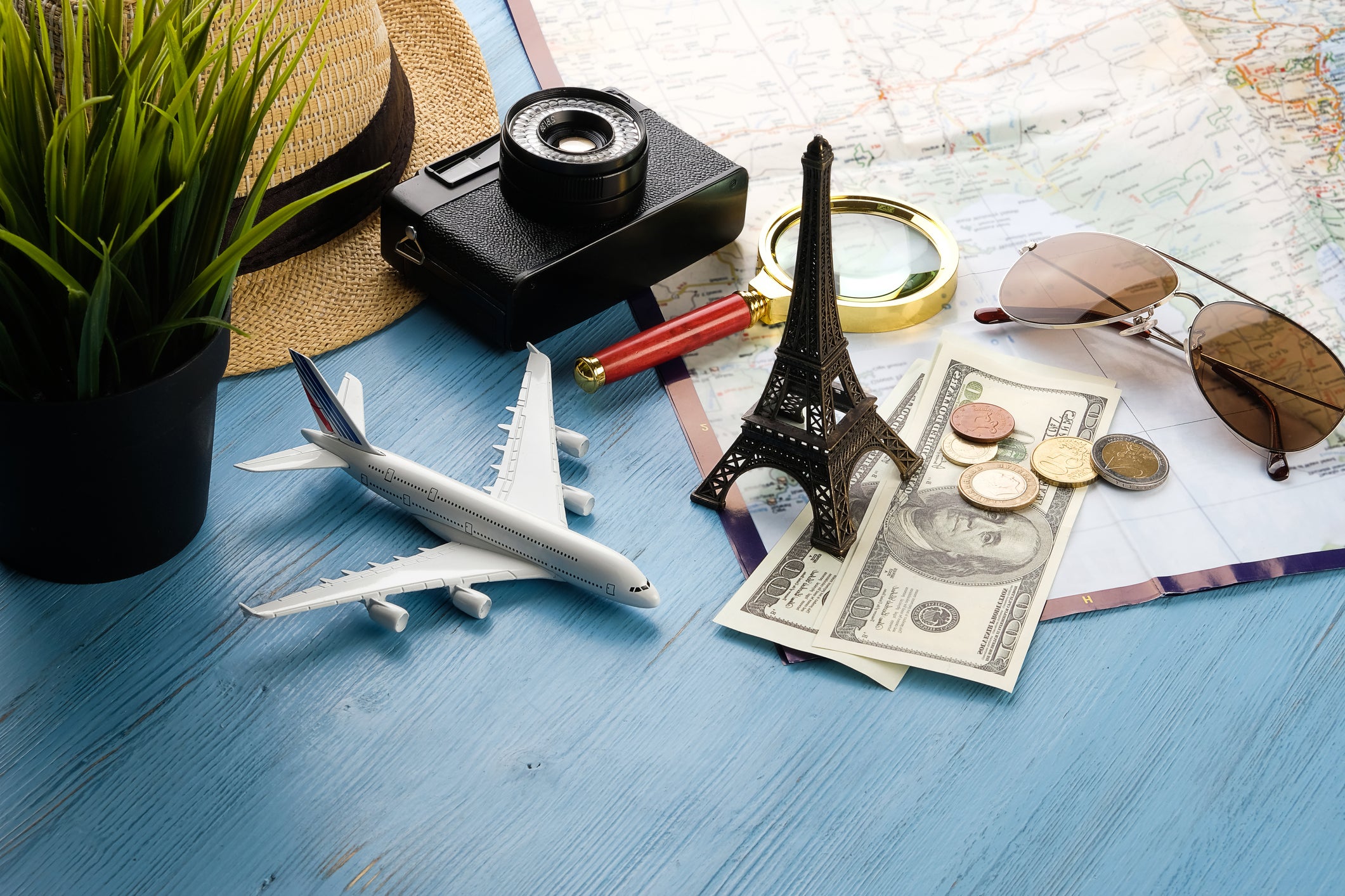 Items For Summer Holidays: Camera, Sunglasses, Cash, Straw Hat, Mobile Phone, Map And Travel Plan. Tourist layout-set and accessories of the Traveler, On a wooden background. Open borders concept for free happy travel. A copy of the text space.