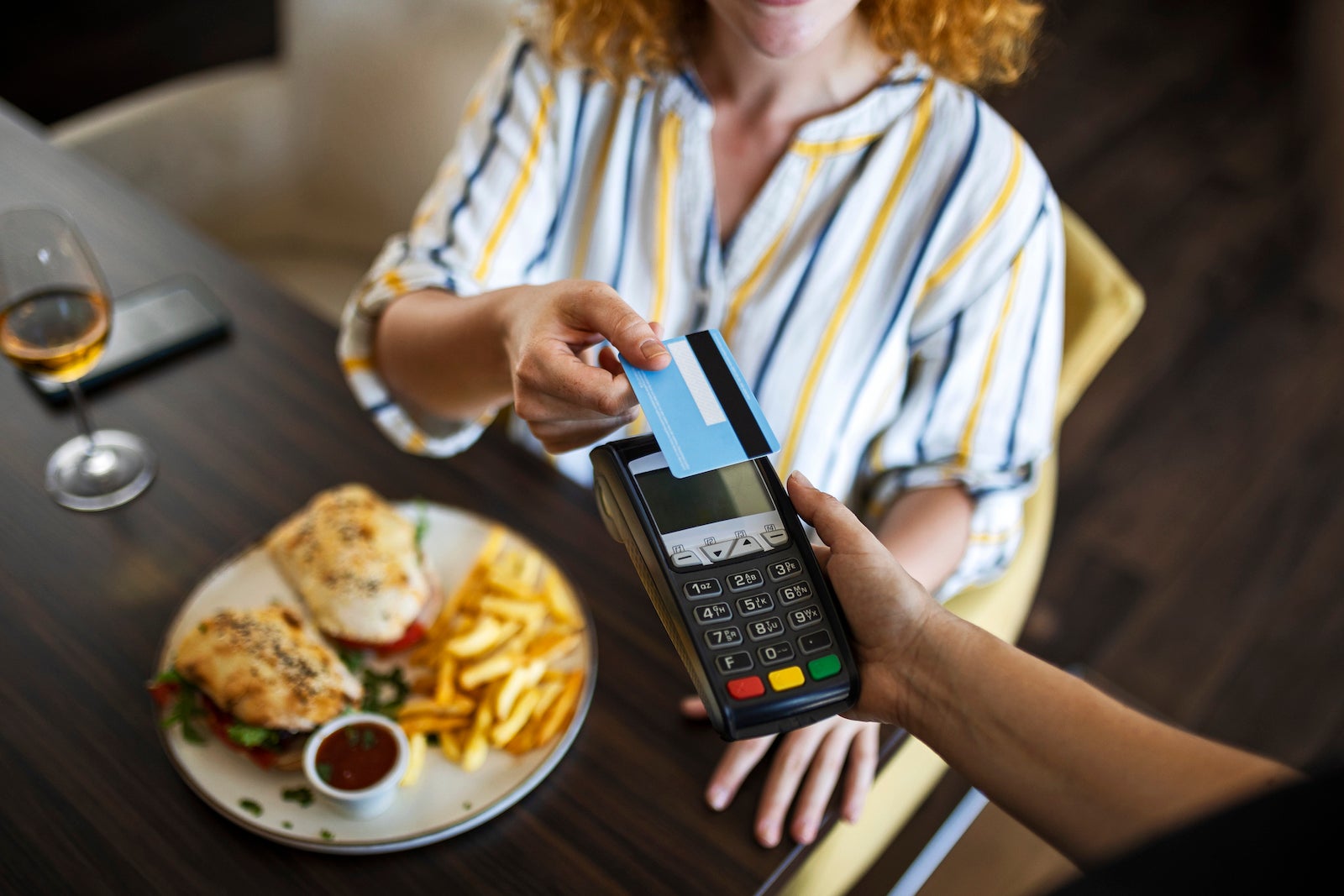 a restaurant customer taps a credit card on a credit card reader to pay for their food