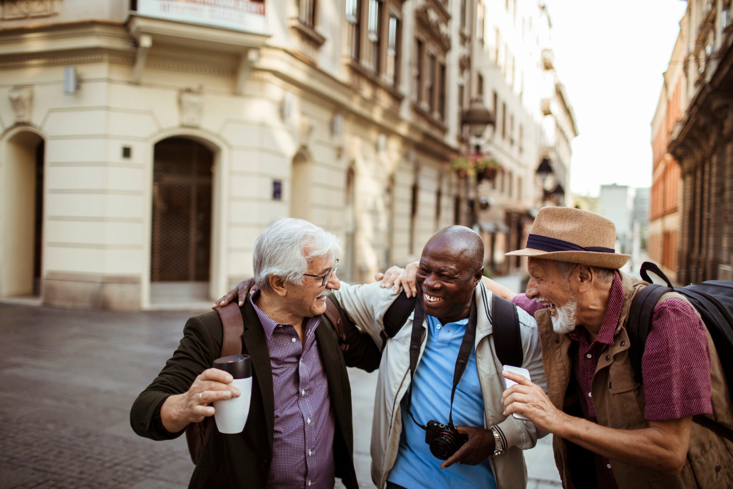 Three senior men laughing in the street