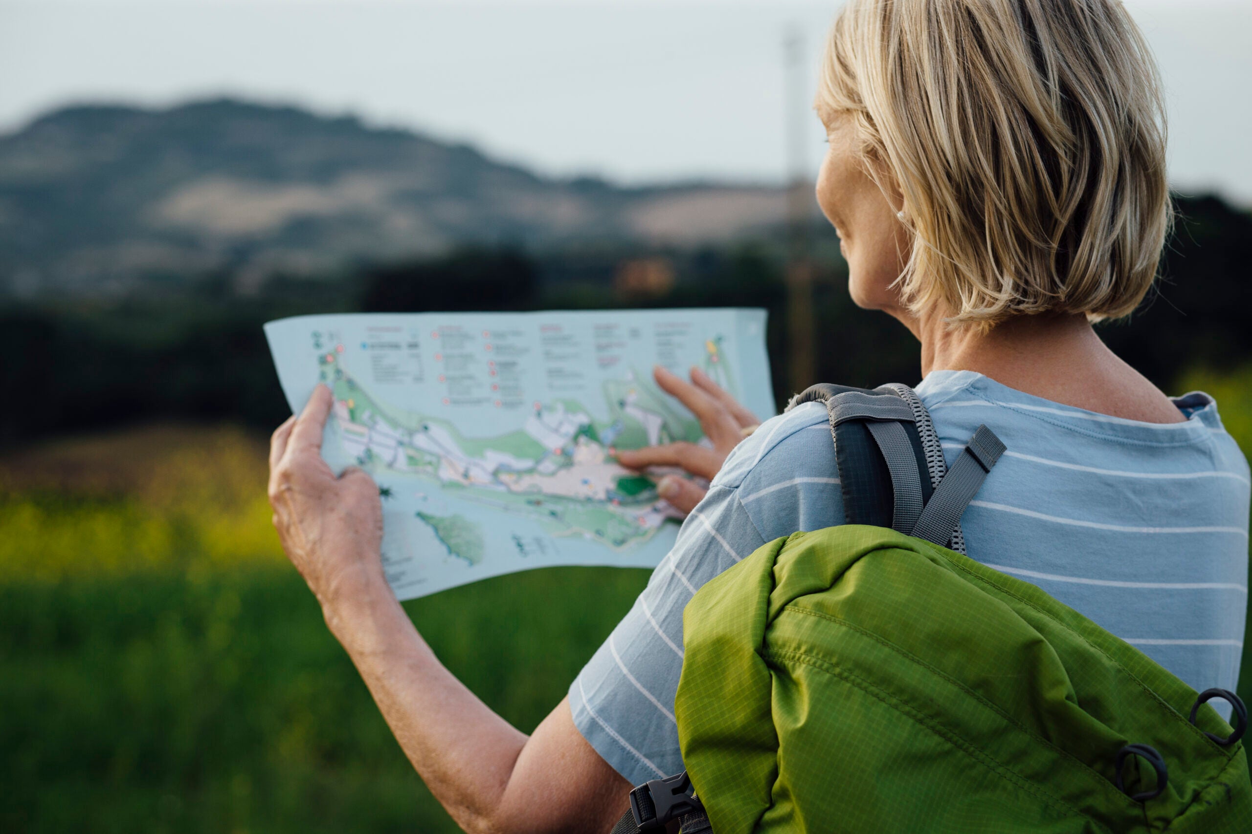 Woman wearing backpack looks at a map