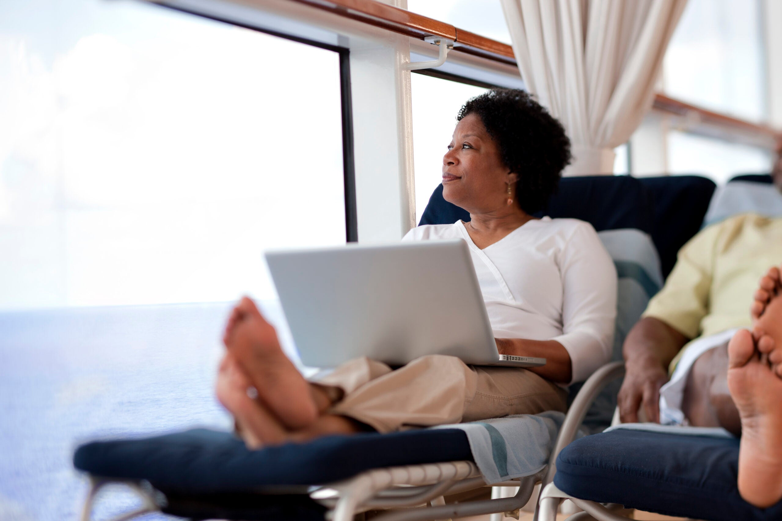 woman lounges with laptop on cruise ship