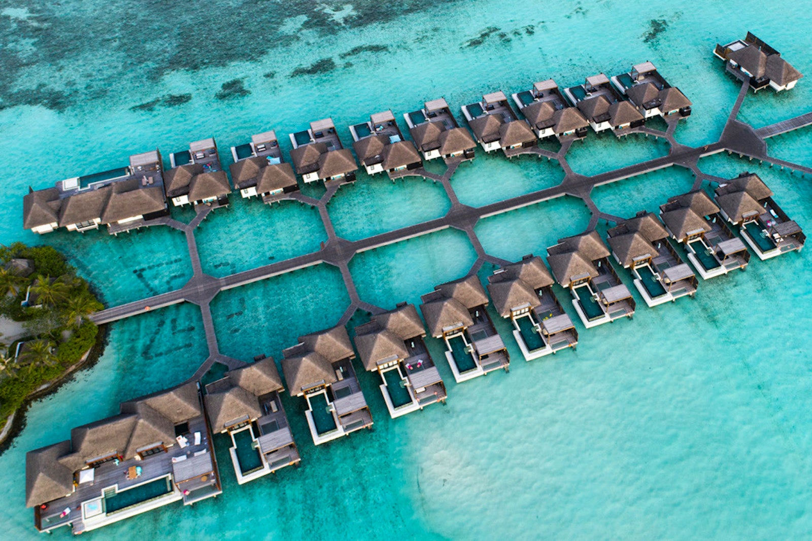 Overwater bungalows sit atop the turquoise blue water connected by walkways