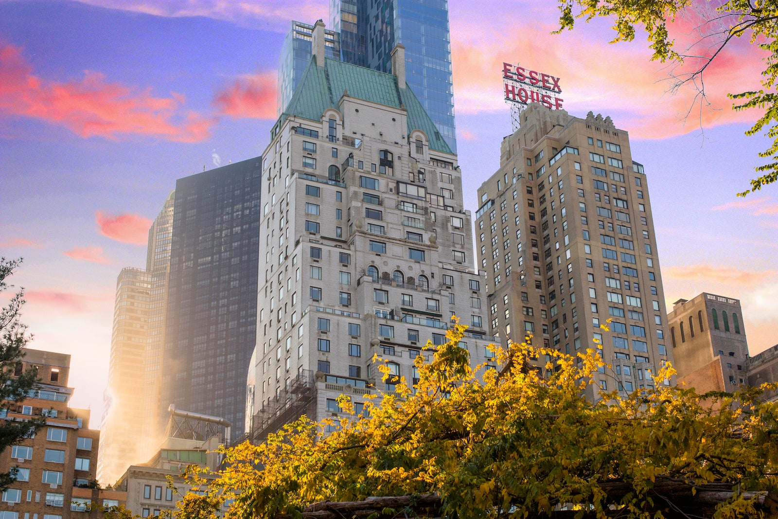 buildings towering of park with fall leaves during orange and blue sunset