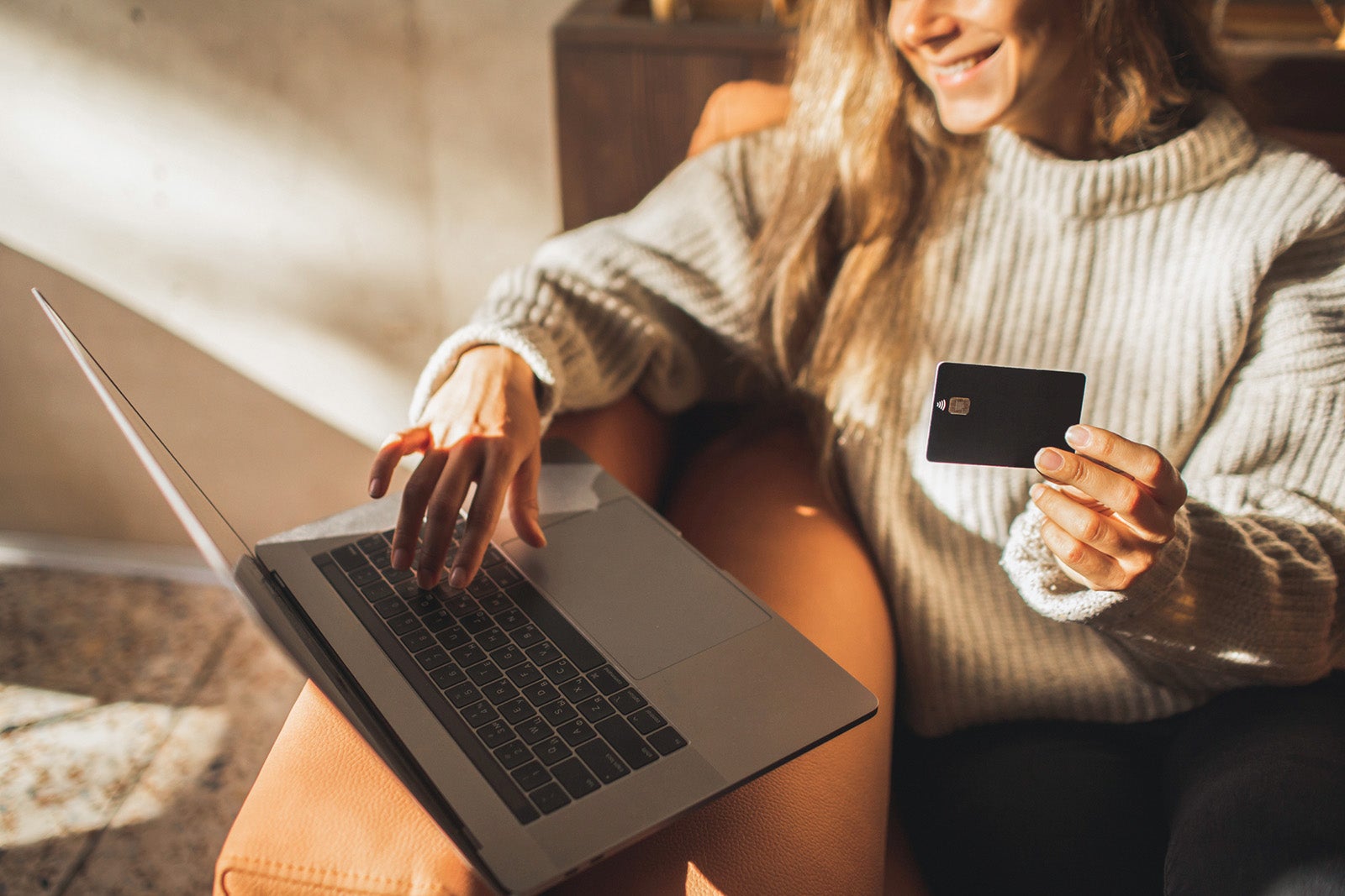 A woman sits in a chair with a laptop in front of her logged in to Credit Journey.