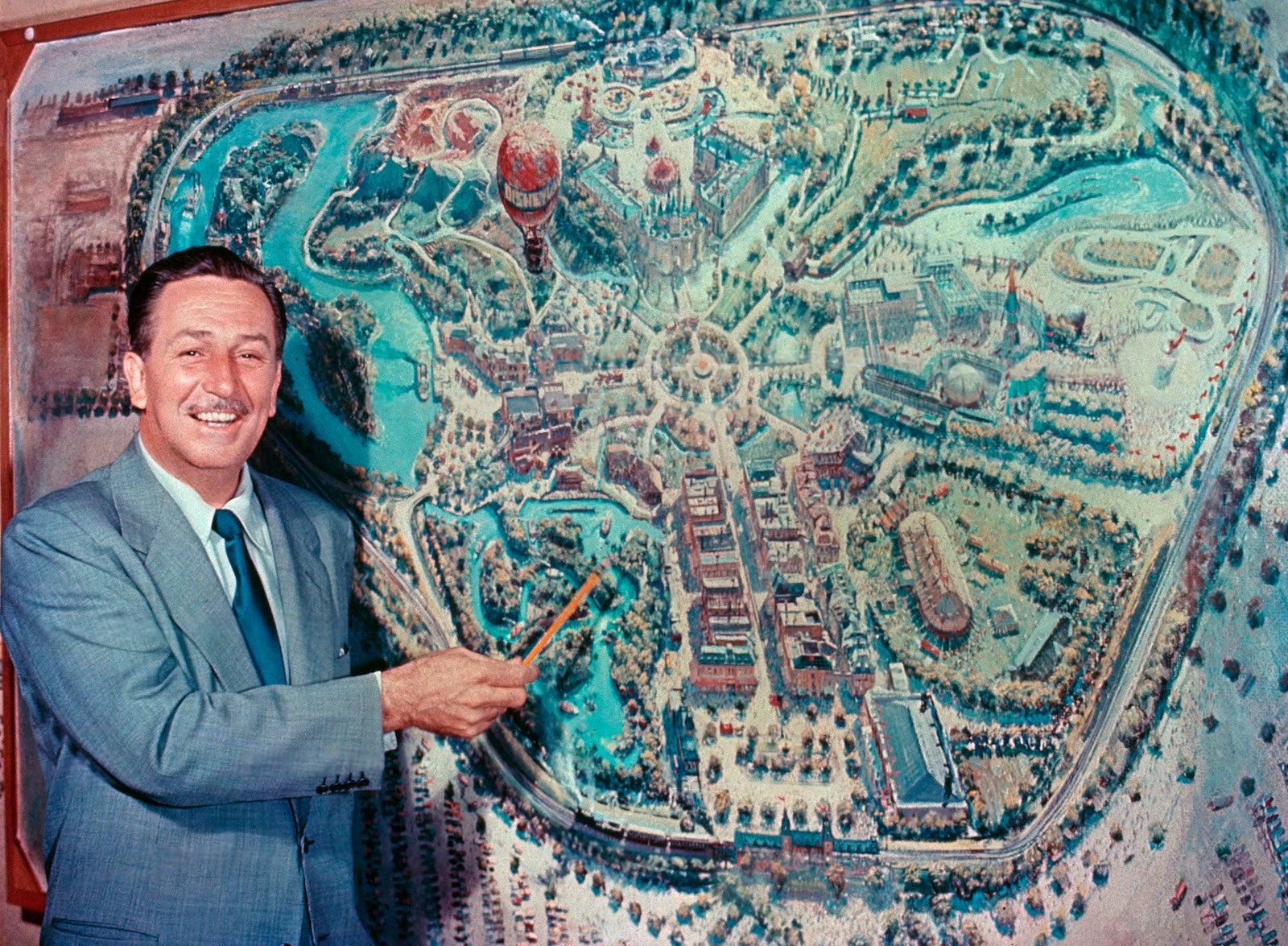 Walt Disney standing in front of map of Disneyland