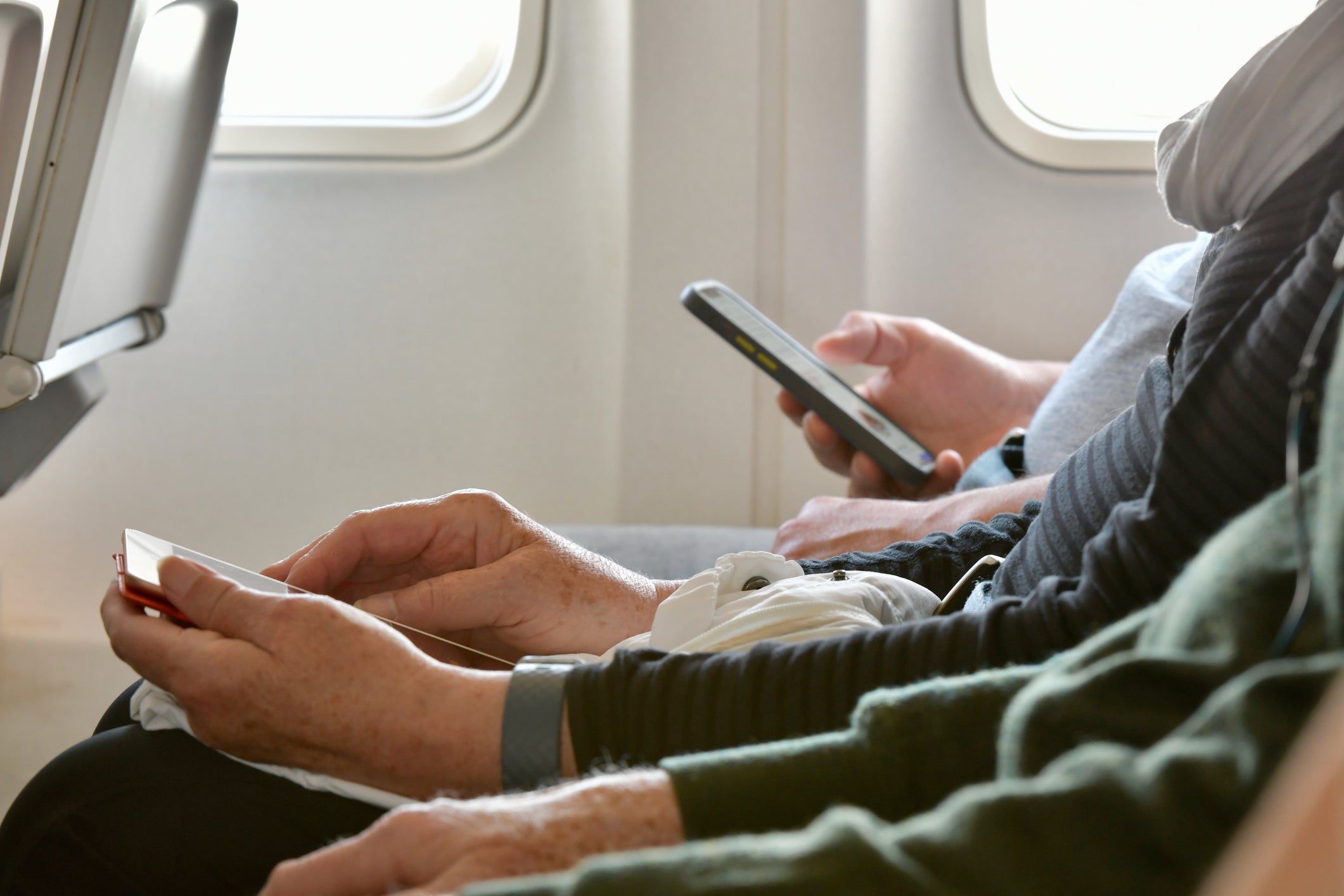 Older person using smartphone on plane