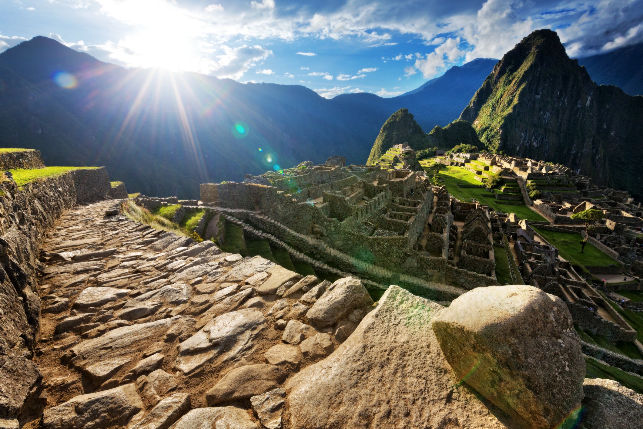 Evening sunburst over deserted paved pathway overlooking Machu Picchu ruins, Peru