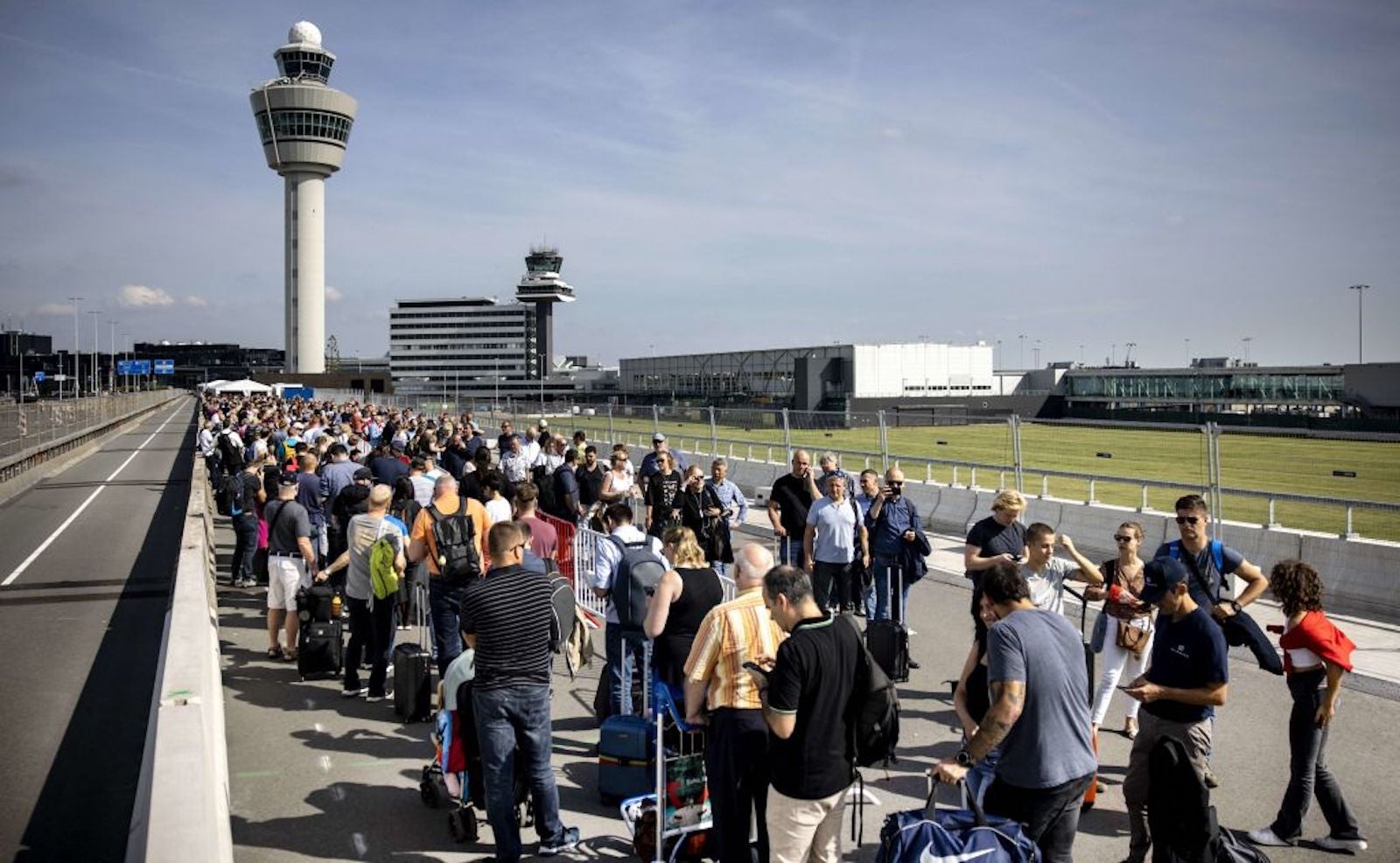 Travelers wait in line outside at Schiphol Airport