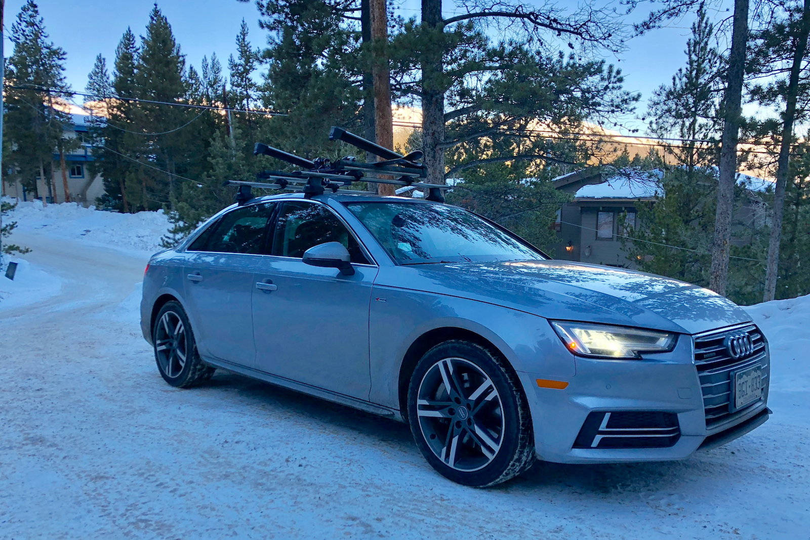 an Audi car with ski rack on top is parked in the snow