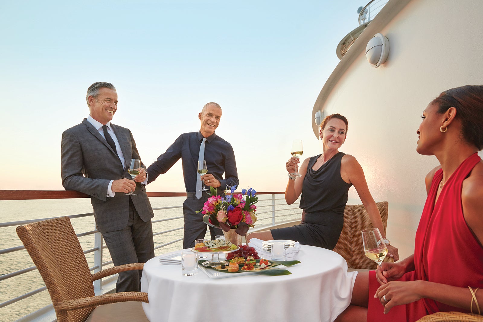 Two couples enjoying drinks on their Seabourn cruise ship balcony