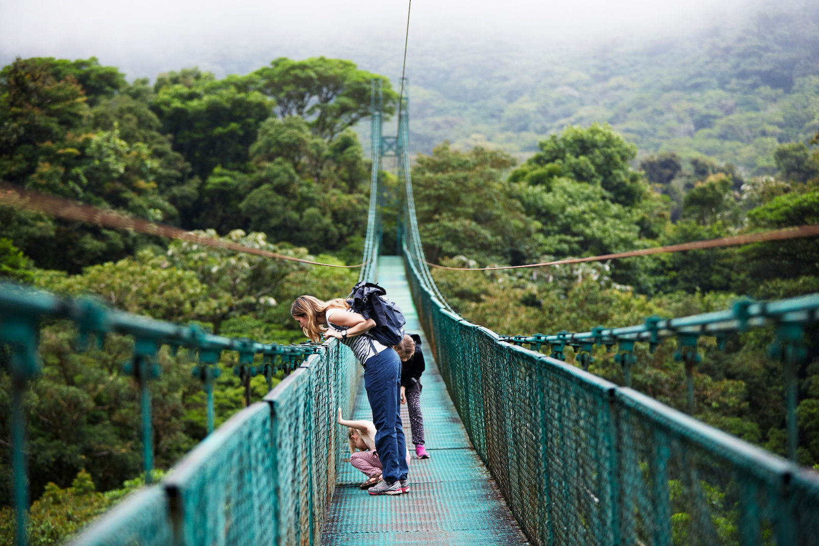 A woman and her daughters on a bridge in the rain forest