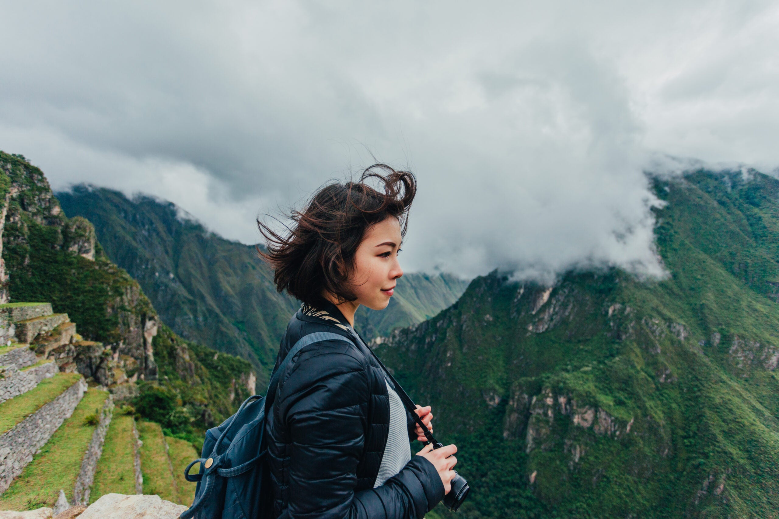 Young Woman Looking At View From Machu Picchu In Peru.