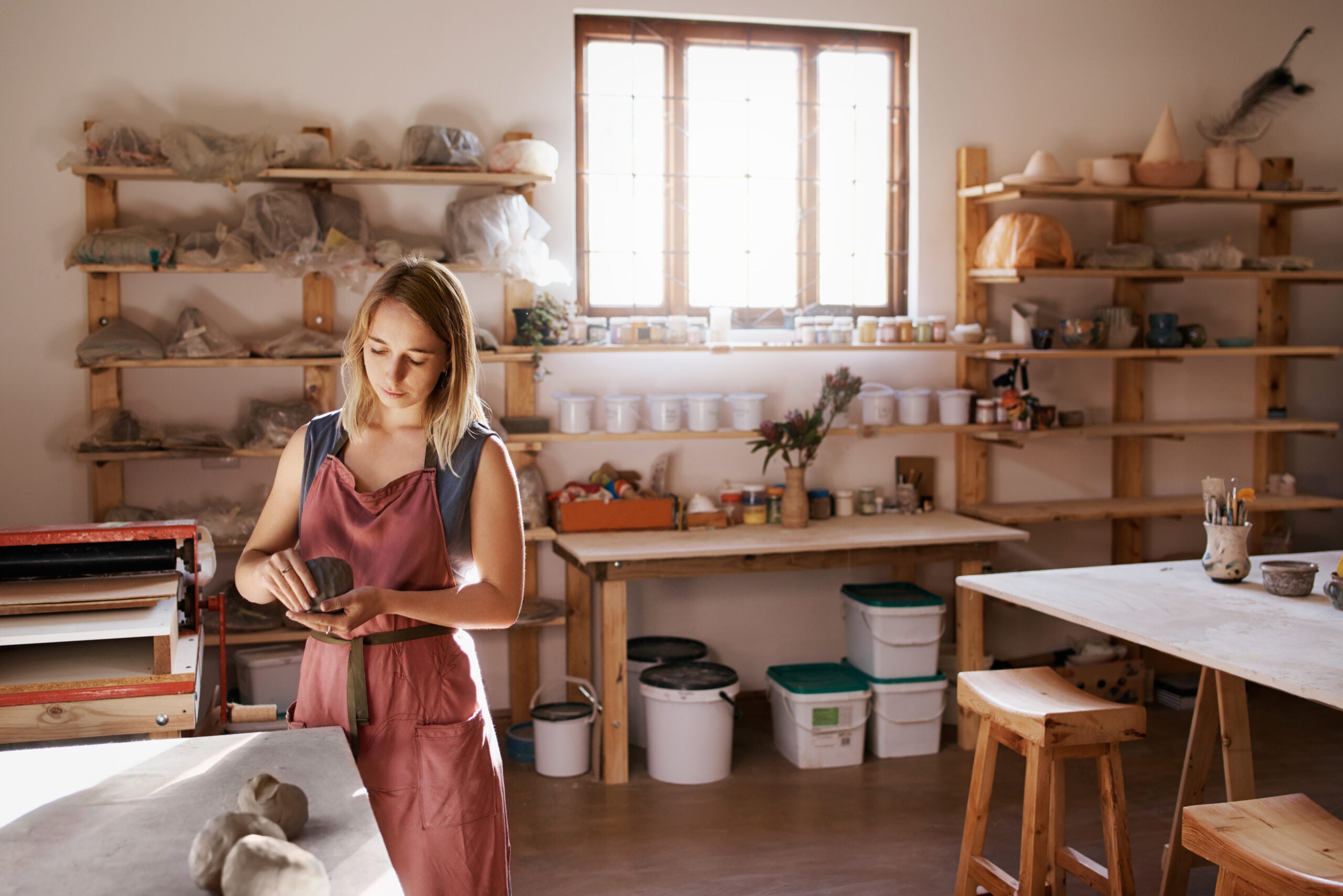 Cropped shot of a woman shaping a clay pot in her workshop