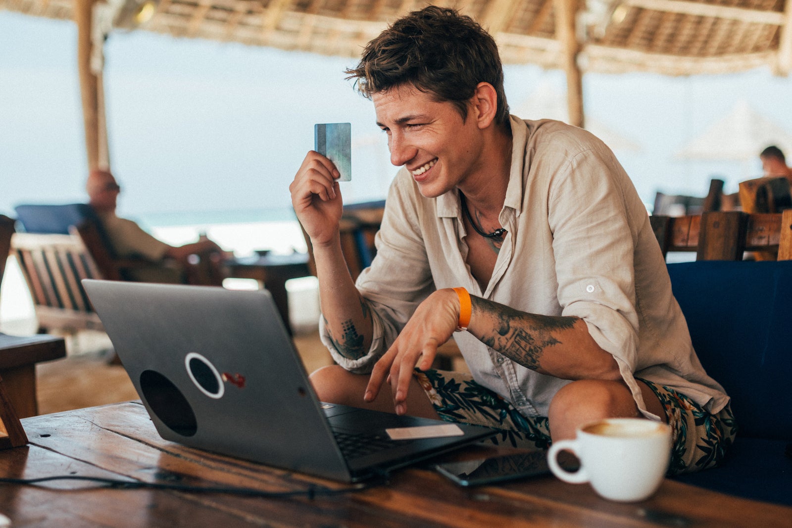 Young man paying online with credit card at the beach bar