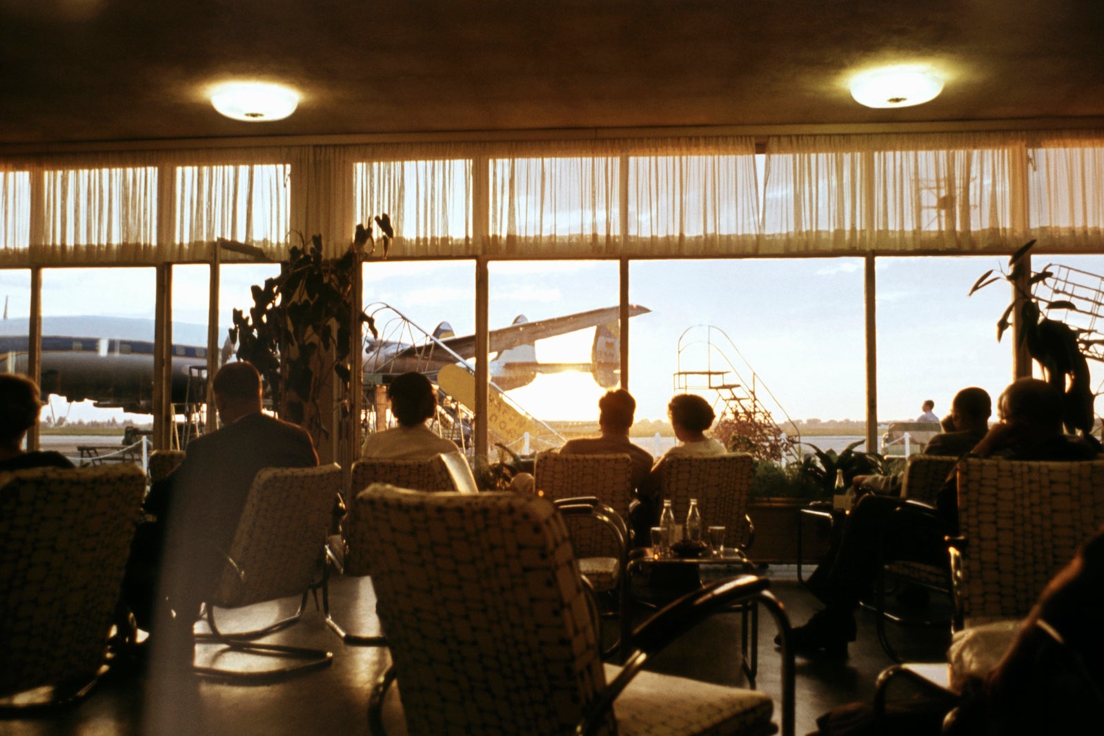 many people watch sunset from the windows of an airport lounge