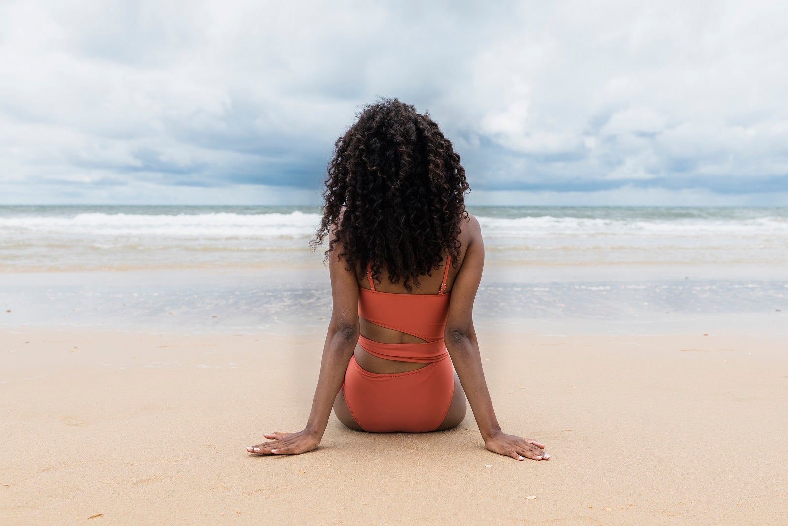 Young woman looking at sea while sitting on sand