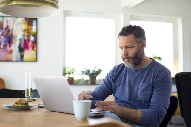 Businessman paying through credit card on laptop at home