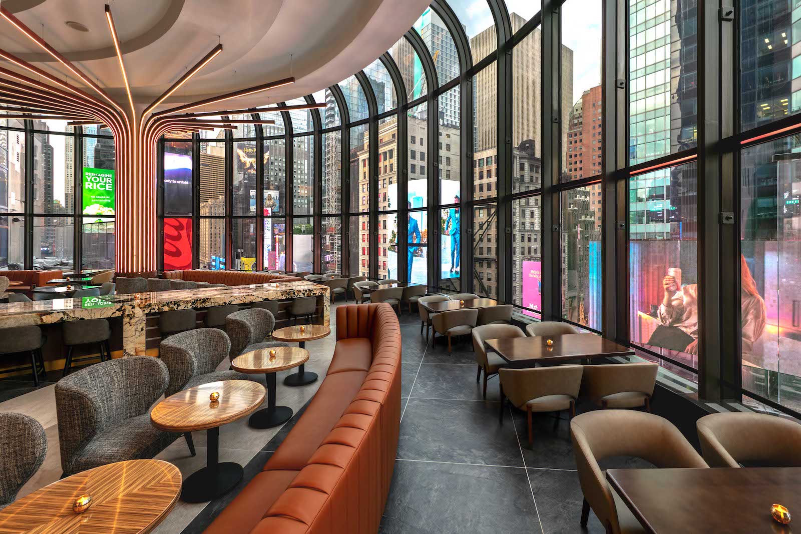 tables around floor-to-ceiling glass windows overlooking large billboards in Times Square