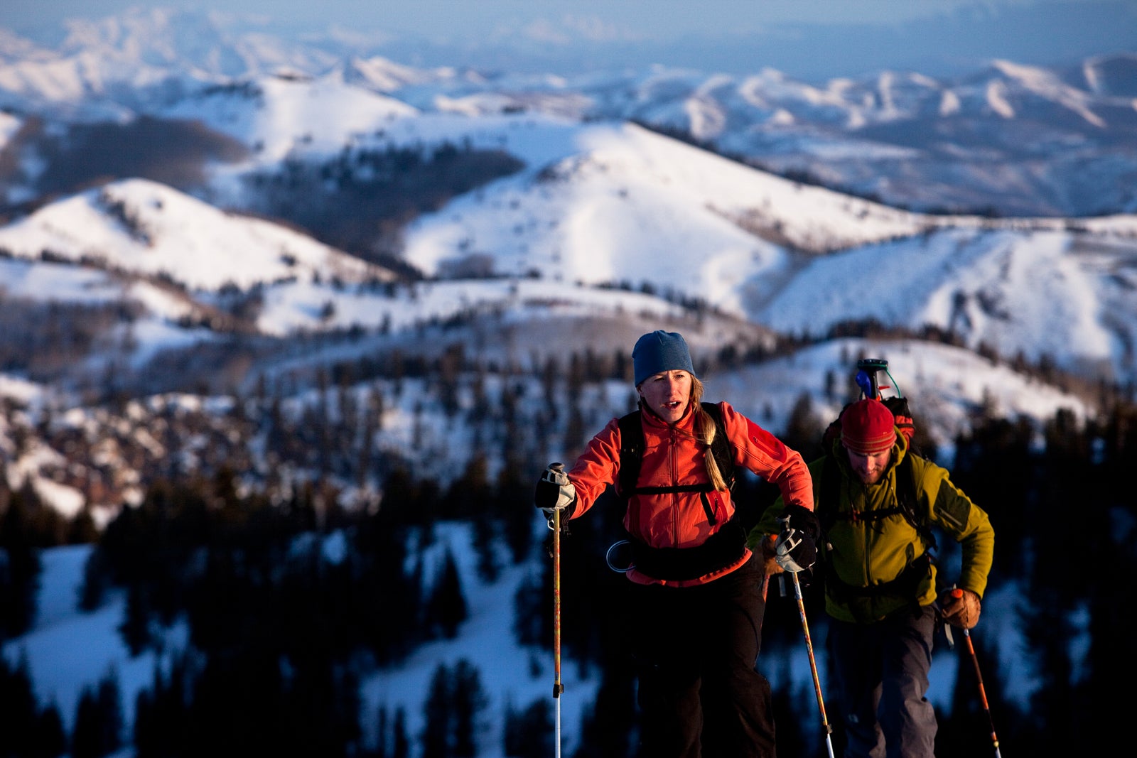 Man and woman backcountry skiers reaching their summit in beautiful sunrise light.