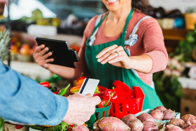 Worker at produce market processing credit card