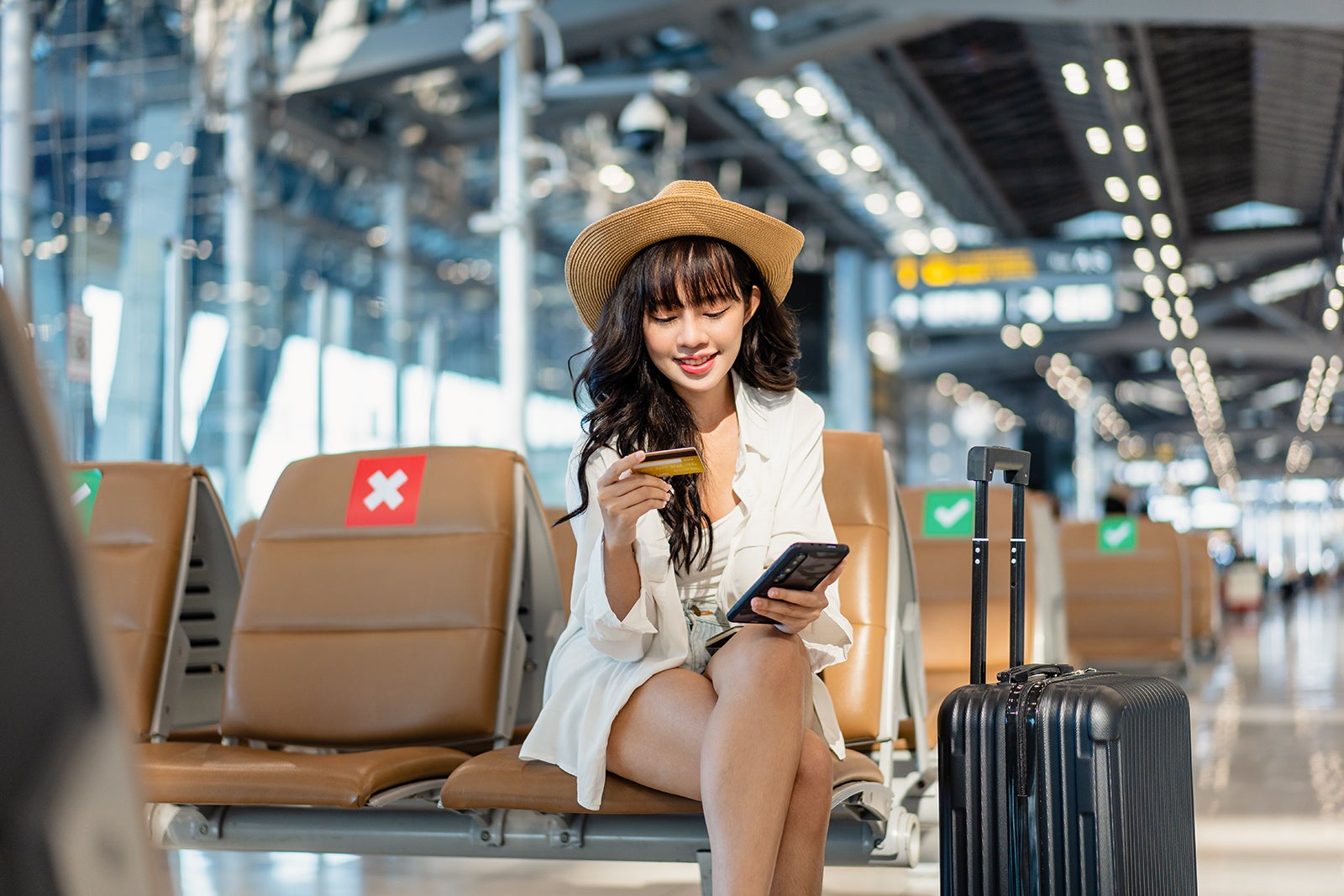 Asian young woman entering credit pin on the smartphone in the airport terminal