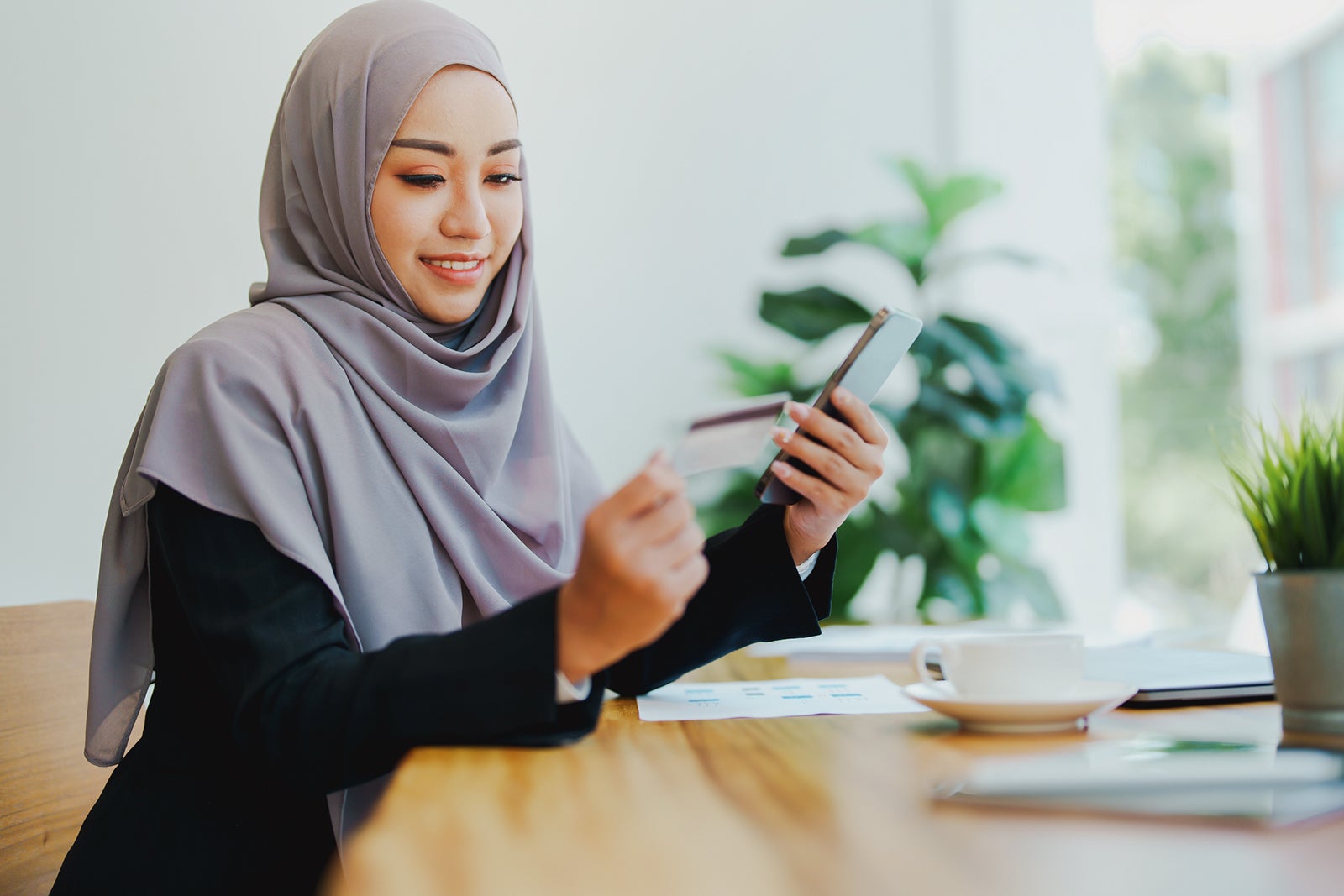 Beautiful Muslim woman shopping online using her phone and credit card