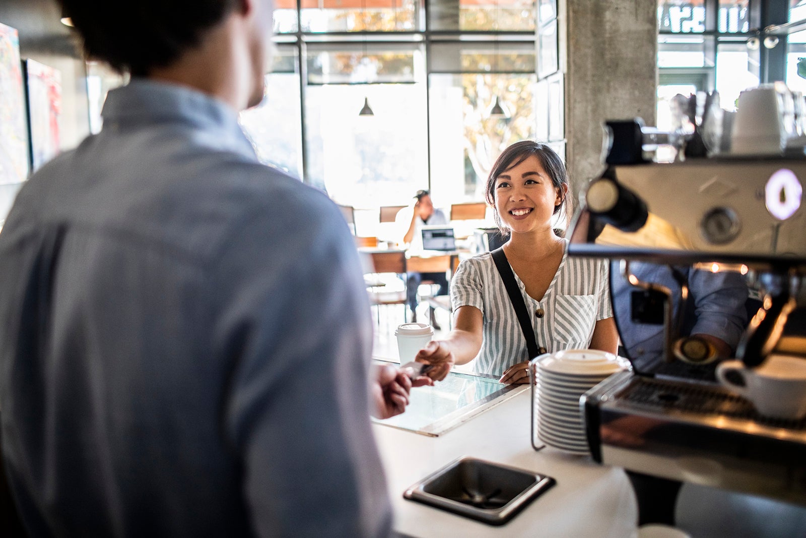 Young woman paying for coffee with credit card