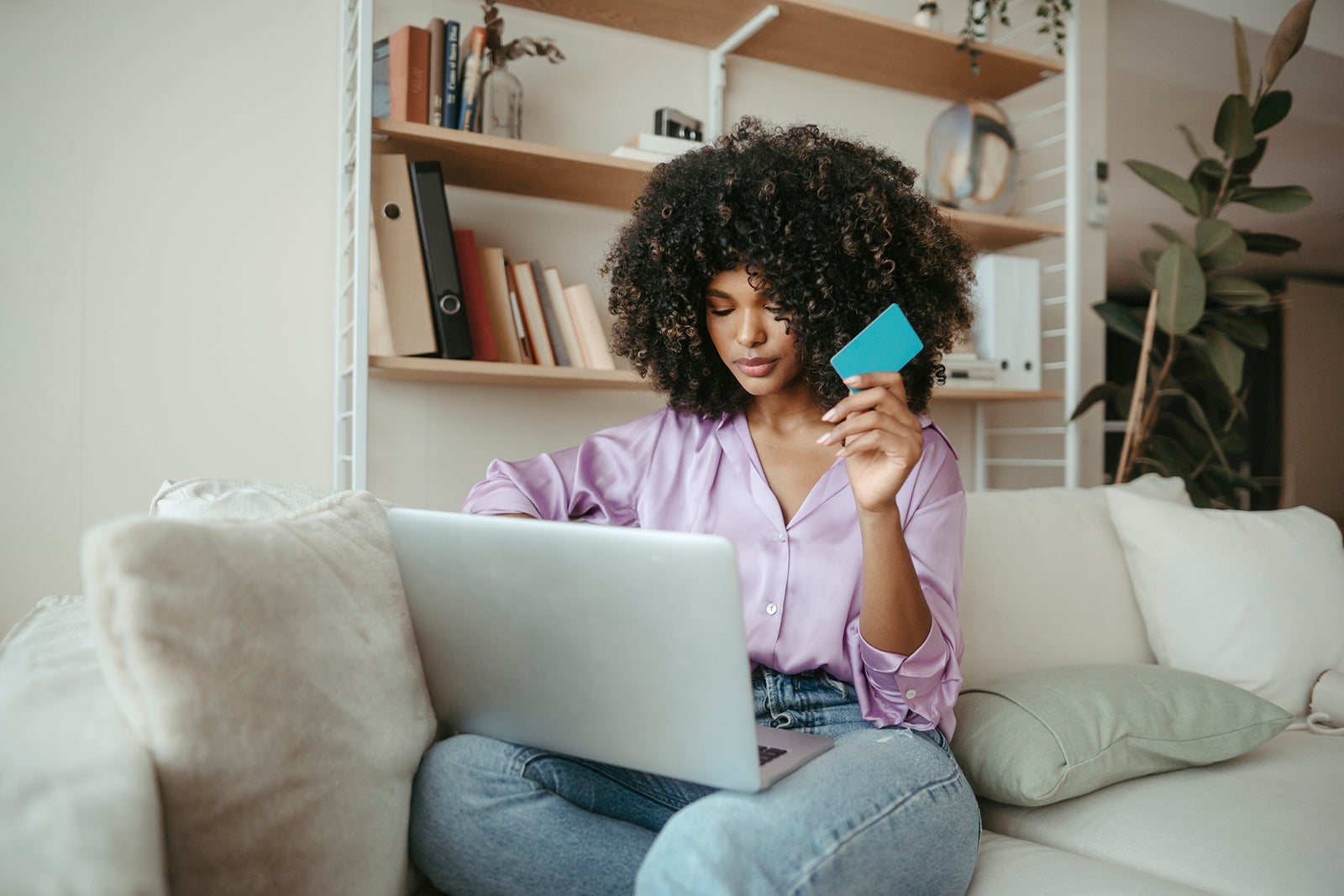 Young woman with credit card doing online shopping on laptop at home