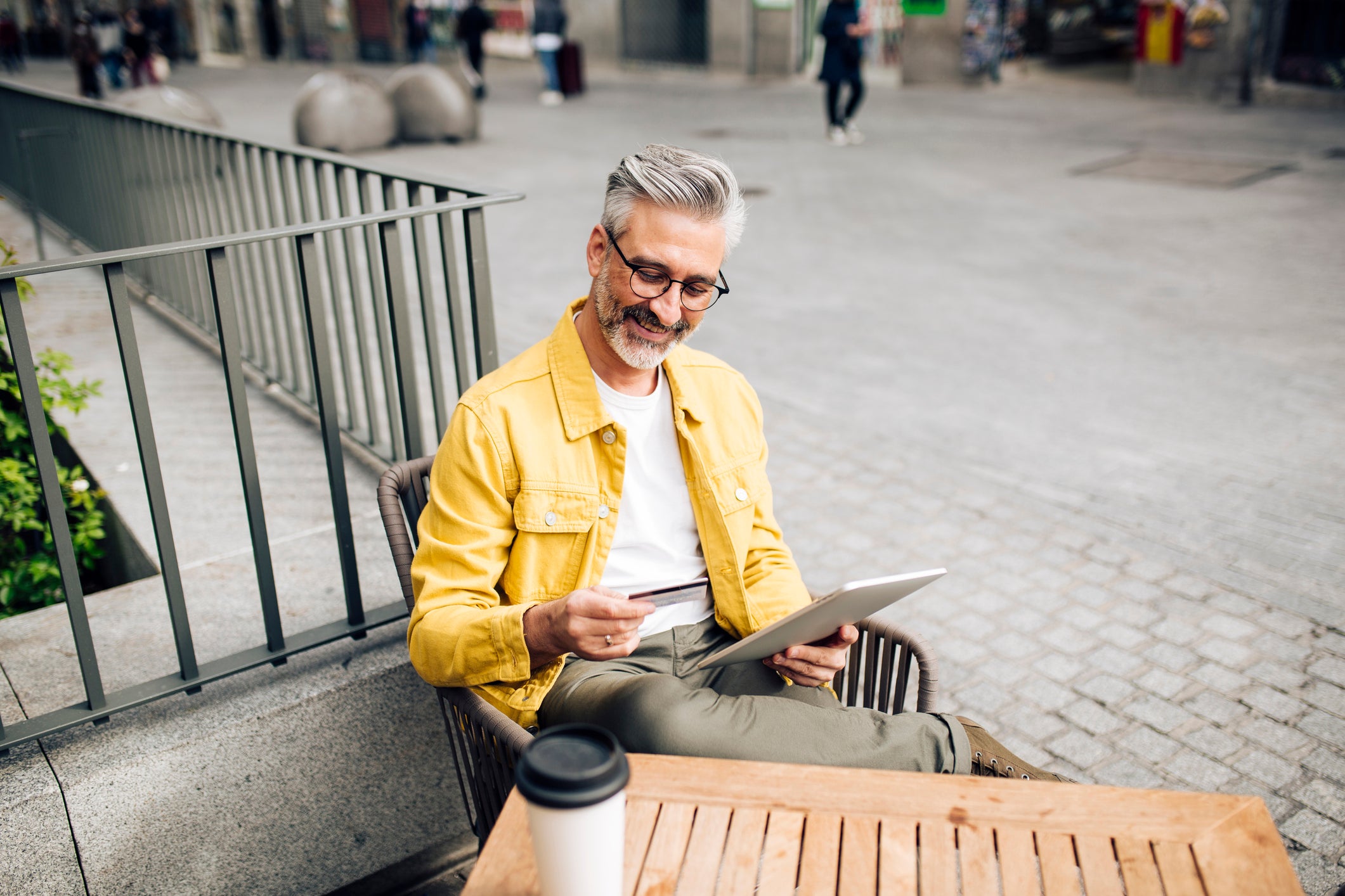 Mature tourist shopping online at the sidewalk cafe